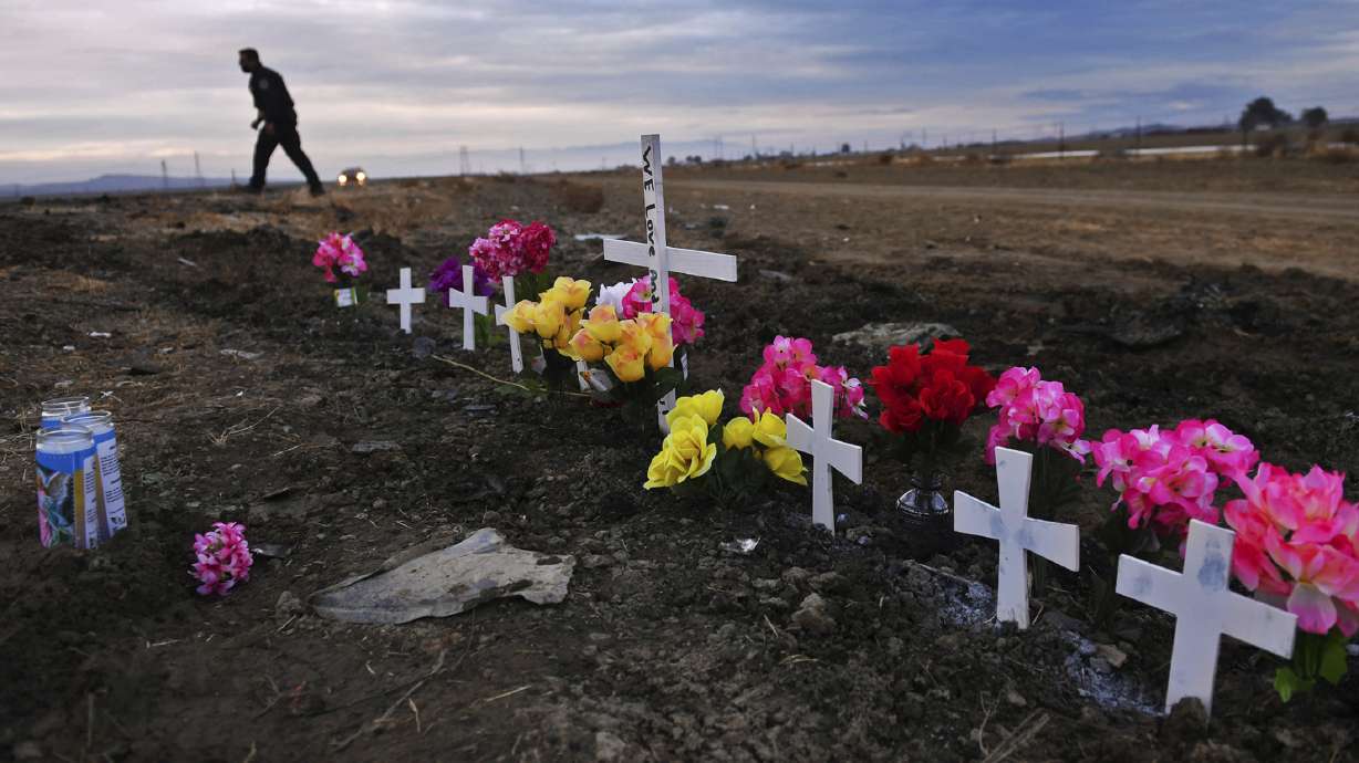 A row of crosses form a memorial along Highway 33 as police officers survey the scene a day after a crash killed nine people south of Coalinga, Calif., Jan. 2, 2021. Investigators said the driver of an SUV involved in the crash was drunk and didn't have a license. The National Transportation Safety Board will use a final report on the crash to launch an effort to lobby for regulations requiring alcohol breath testing devices on all new vehicles.