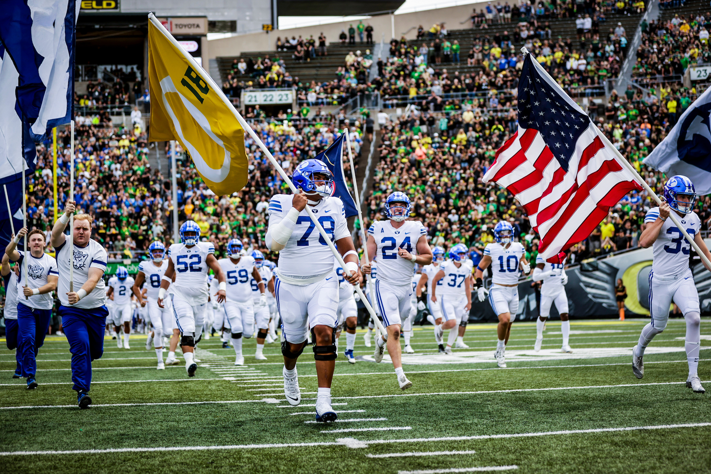 BYU offensive lineman Kingsley Suamataia, an Oregon transfer who prepped at Orem High, runs out a flag with the University of Oregon logo and No. 16 in honor of tight end Spencer Webb, who tragically died over the summer in a climbing accident, prior to the Cougars' game against the Ducks, Saturday, Sept. 17, 2022 at Autzen Stadium in Eugene, Oregon.