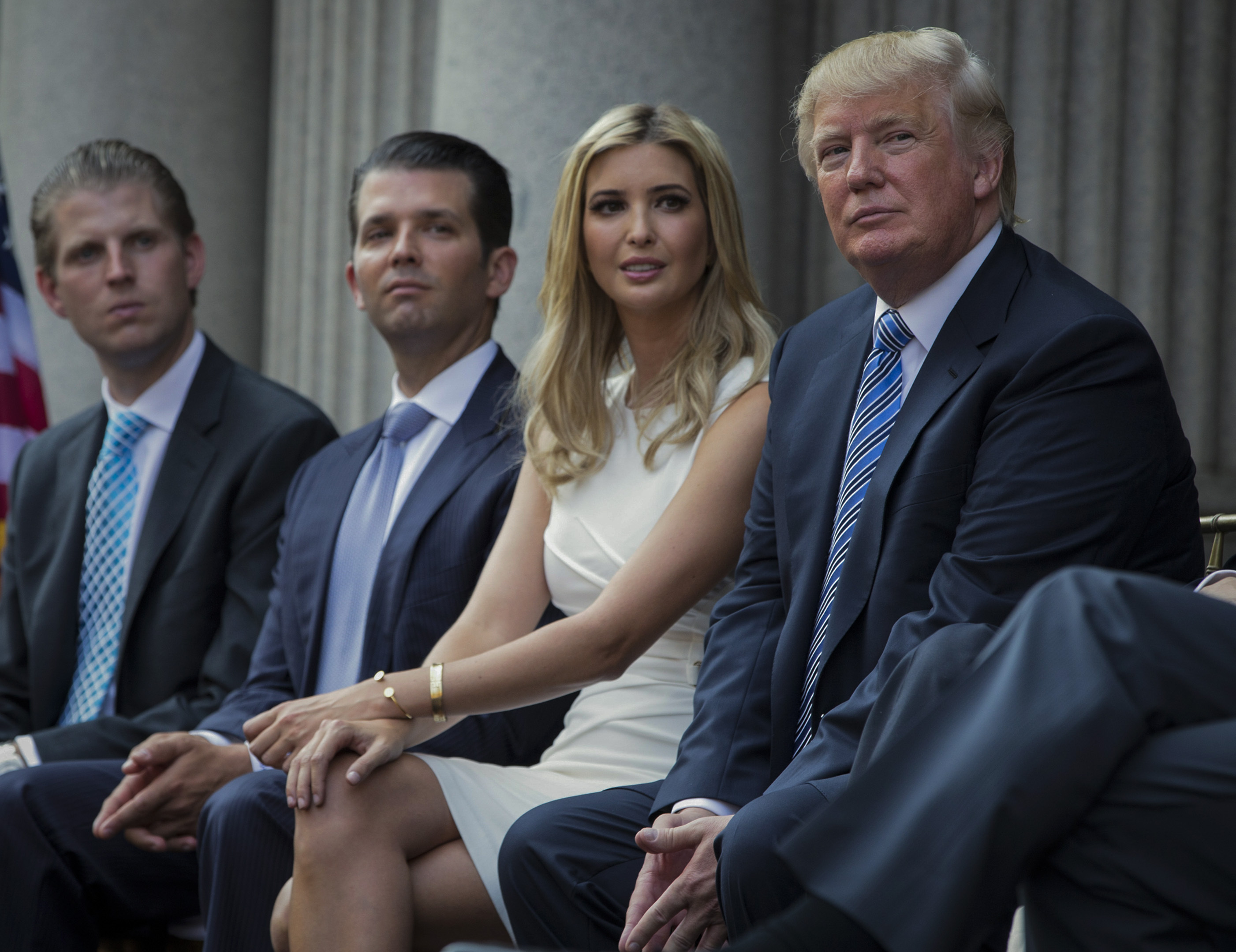 Donald Trump, right, sits with his children, from left, Eric Trump, Donald Trump Jr., and Ivanka Trump during a groundbreaking ceremony for the Trump International Hotel on July 23, 2014, in Washington. New York’s attorney general sued Trump and his company on Wednesday, alleging business fraud involving some of their most prized assets, including properties in Manhattan, Chicago and Washington, D.C.