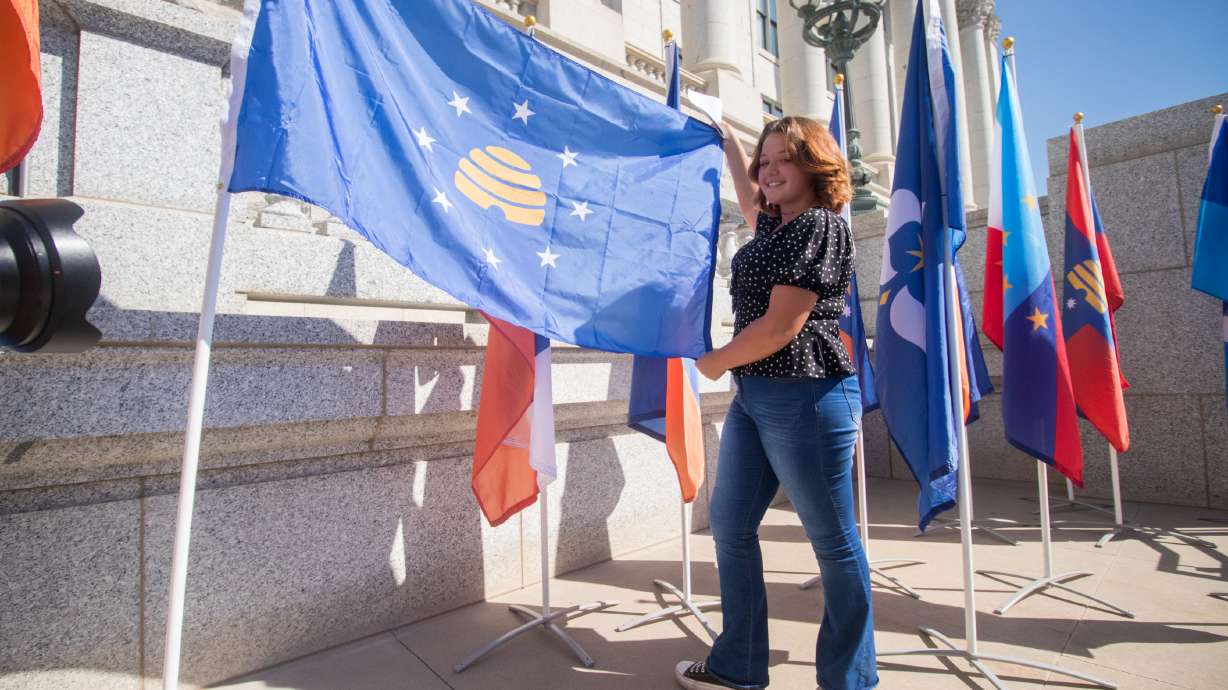 Angelina Nading, a junior at Uintah High School in Vernal, poses with her Utah state flag design outside of the state Capitol on Thursday. Her design is one of 20 semifinalists now on display in Salt Lake City, Cedar City and Logan while the state narrows the field down for a potential new state flag.