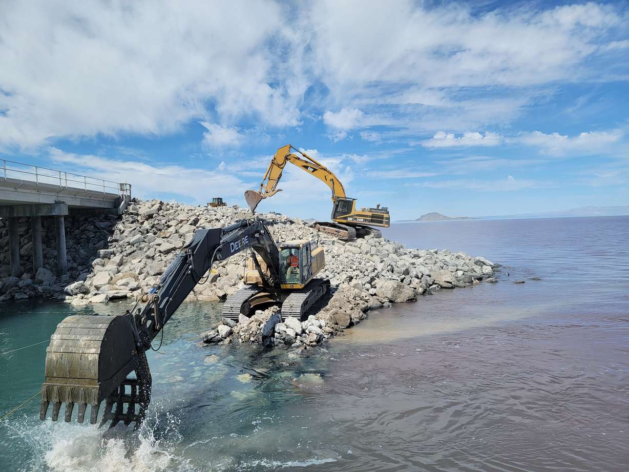 An excavator moves stones by the Great Salt Lake Causeway to raise the berm by 4 feet in July 2022.