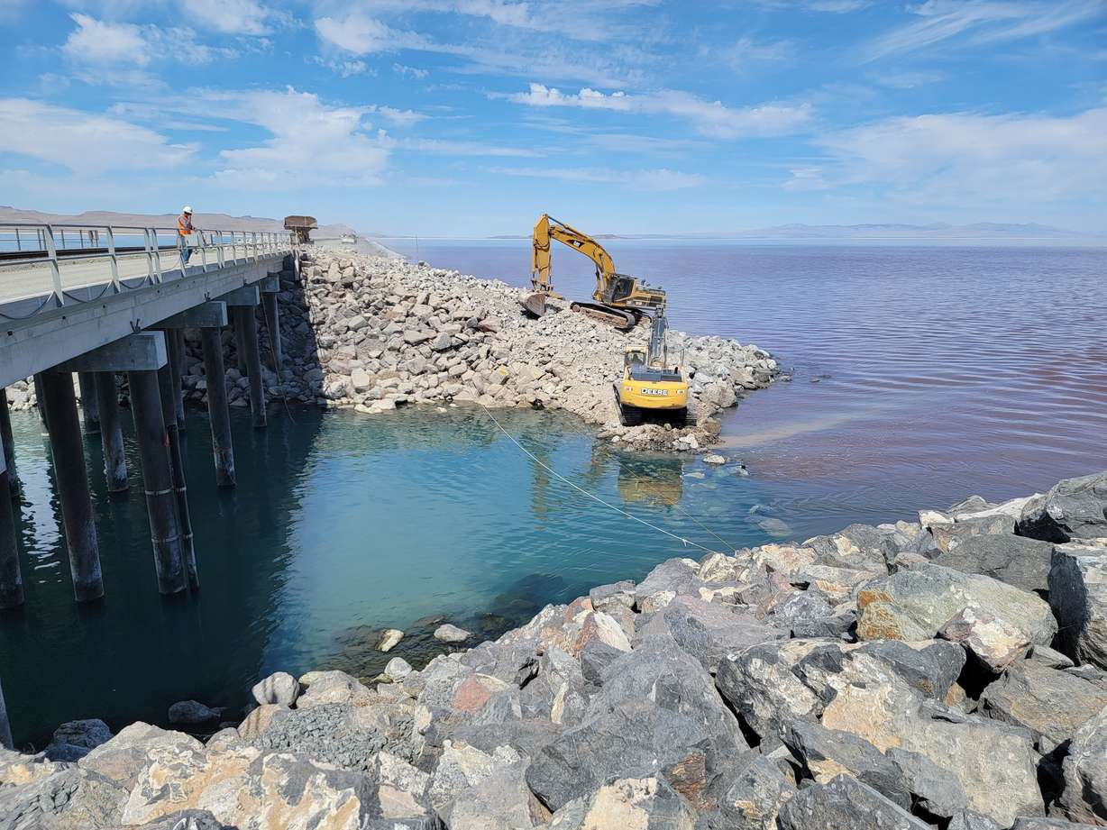 Crews use an excavator to move stones at the Great Salt Lake Causeway to raise the berm by 4 feet in July. The higher berm is expected to help the health of the lake, experts say.