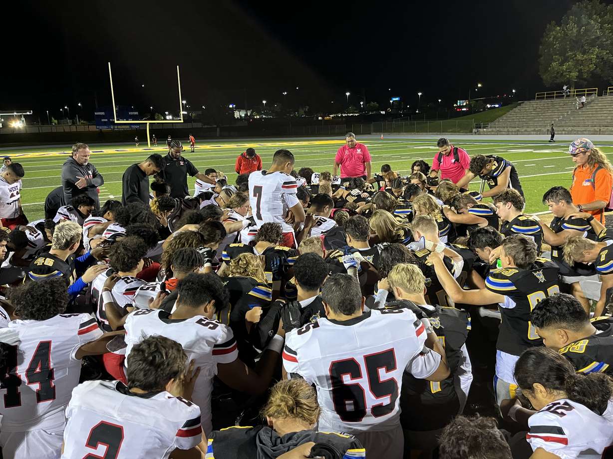 West quarterback Isaiah SueSue, center, prays with his teammates and players from Taylorsville for a wounded Warrior special-teams player after the Panthers' high school football game, Thursday, Sept. 22, 2022 at Taylorsville.