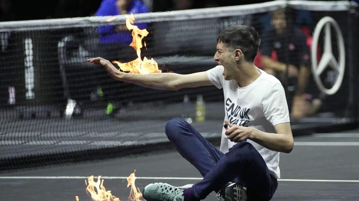 A man sets fire on his hand during protest at a match Team World's Diego Schwartzman against Team Europe's Stefanos Tsitsipas on day one of the Laver Cup tennis tournament at the O2 in London, Friday, Sept. 23, 2022.
