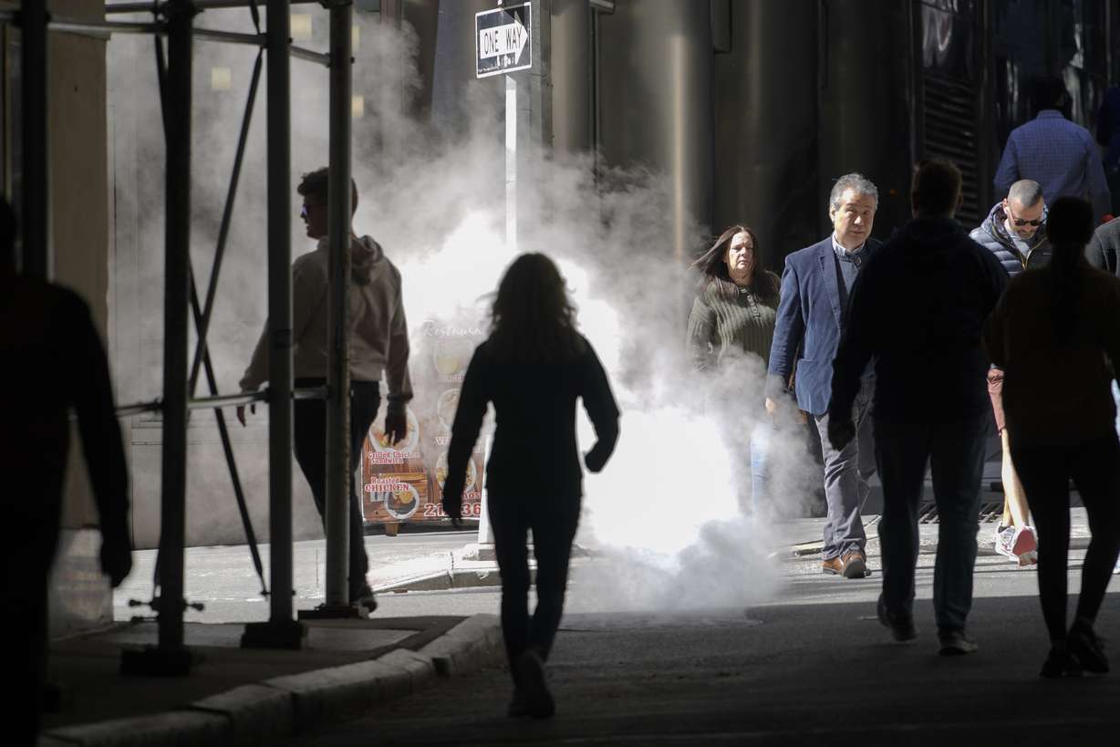 Pedestrian walk in an alley next to the New York Stock Exchange, Friday, in New York. Stocks tumbled worldwide Friday on more signs the global economy is weakening, just as central banks raise the pressure even more with additional interest rate hikes.