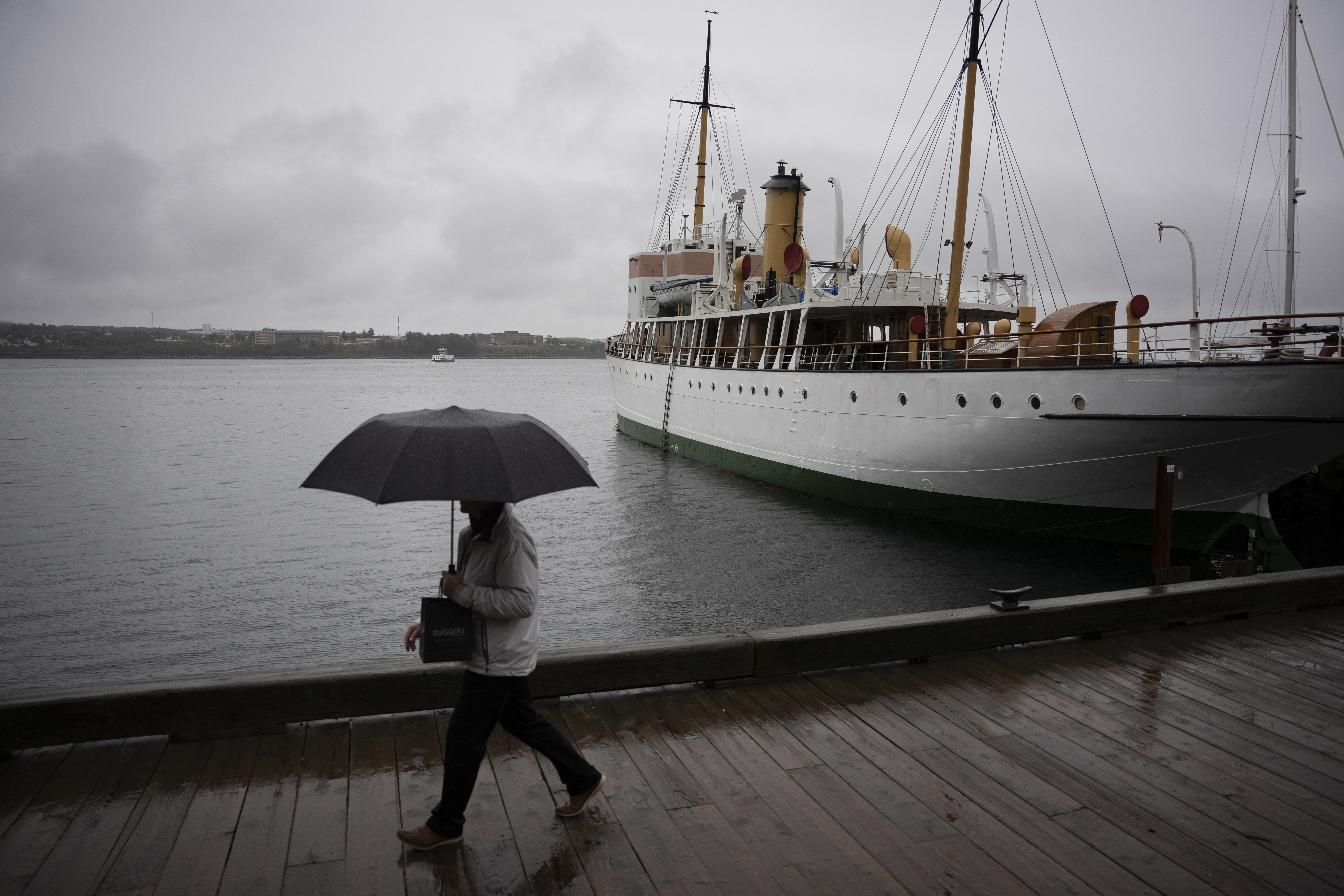 A pedestrian shields themselves with an umbrella while walking along the Halifax waterfront as rain falls ahead of Hurricane Fiona making landfall in Halifax, Friday.