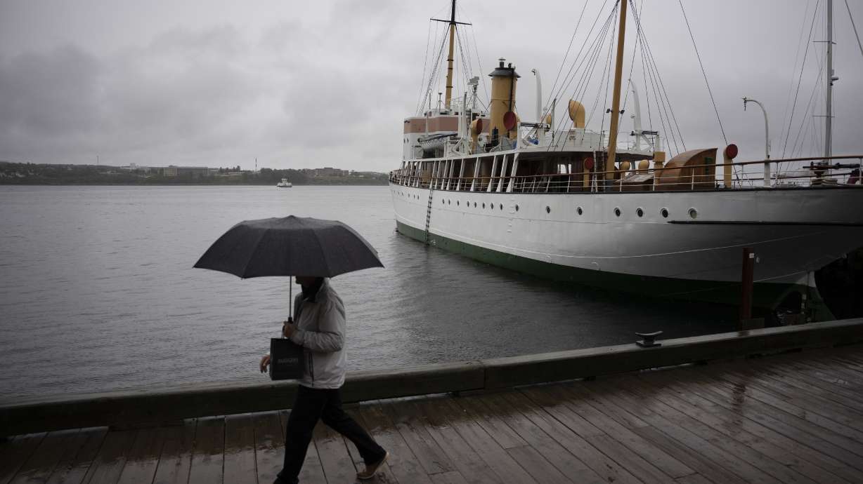 A pedestrian shields themselves with an umbrella while walking along the Halifax waterfront as rain falls ahead of Hurricane Fiona making landfall in Halifax, Friday.