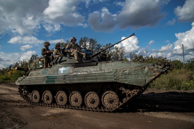 Ukrainian service members ride atop an armored fighting vehicles, amid Russia's attack on Ukraine, in Kharkiv region, Ukraine, Saturday.
