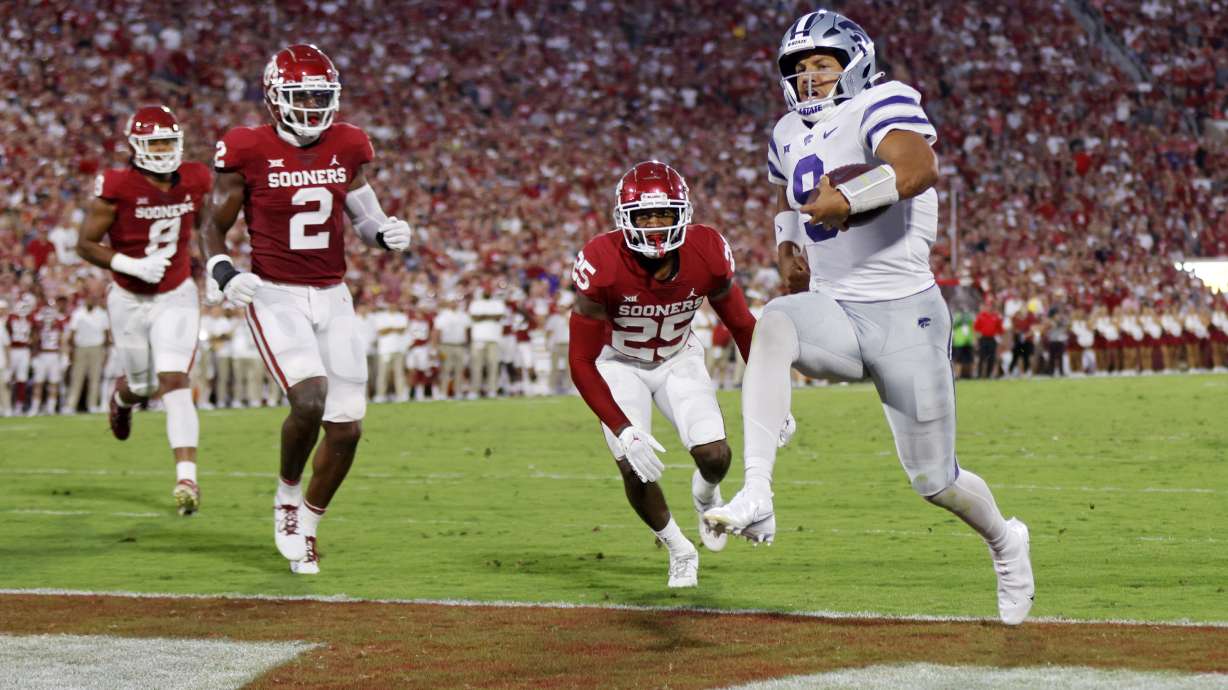 Kansas State quarterback Adrian Martinez (9) carries the ball for a touchdown past Oklahoma defensive lineman Jonah Laulu (8), left, linebacker David Ugwoegbu (2) and defensive back Justin Broiles (25) in the first half of an NCAA college football game, Saturday, Sept. 24, 2022, in Norman, Okla.