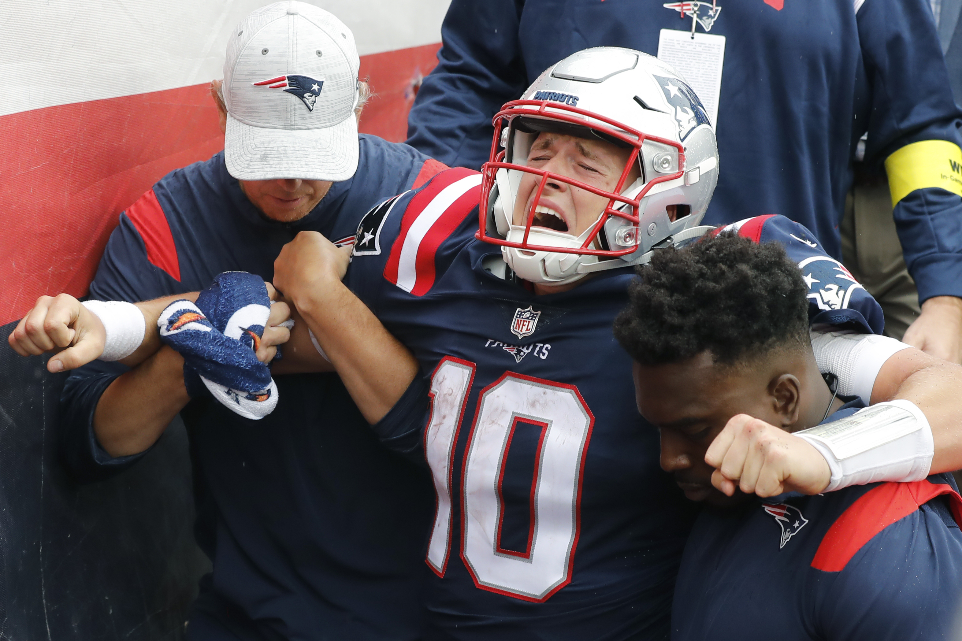 New England Patriots quarterback Mac Jones (10) is helped off the field after suffering a leg injury with less than two minutes to play in the second half of an NFL football game against the Baltimore Ravens, Sunday, Sept. 25, 2022, in Foxborough, Mass. 