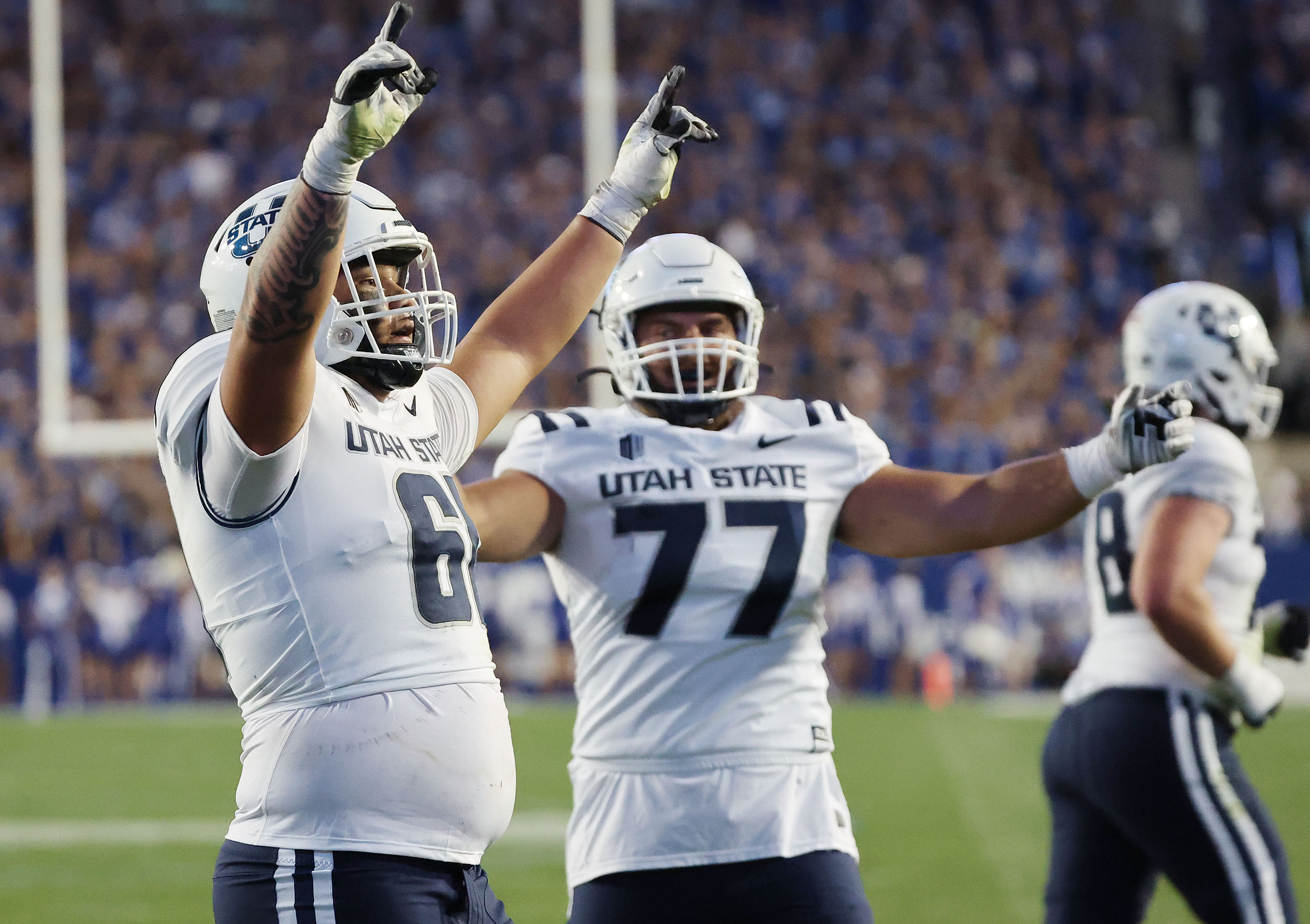 Utah State Aggies offensive lineman Weylin Lapuaho (61) and Utah State Aggies offensive lineman Calvin Knapp (77) celebrate a touchdown in Provo on Thursday, Sept. 29, 2022.