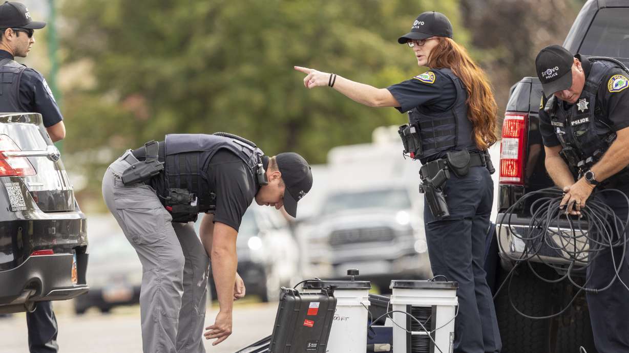 Officers set up equipment during a standoff in Orem on Thursday.