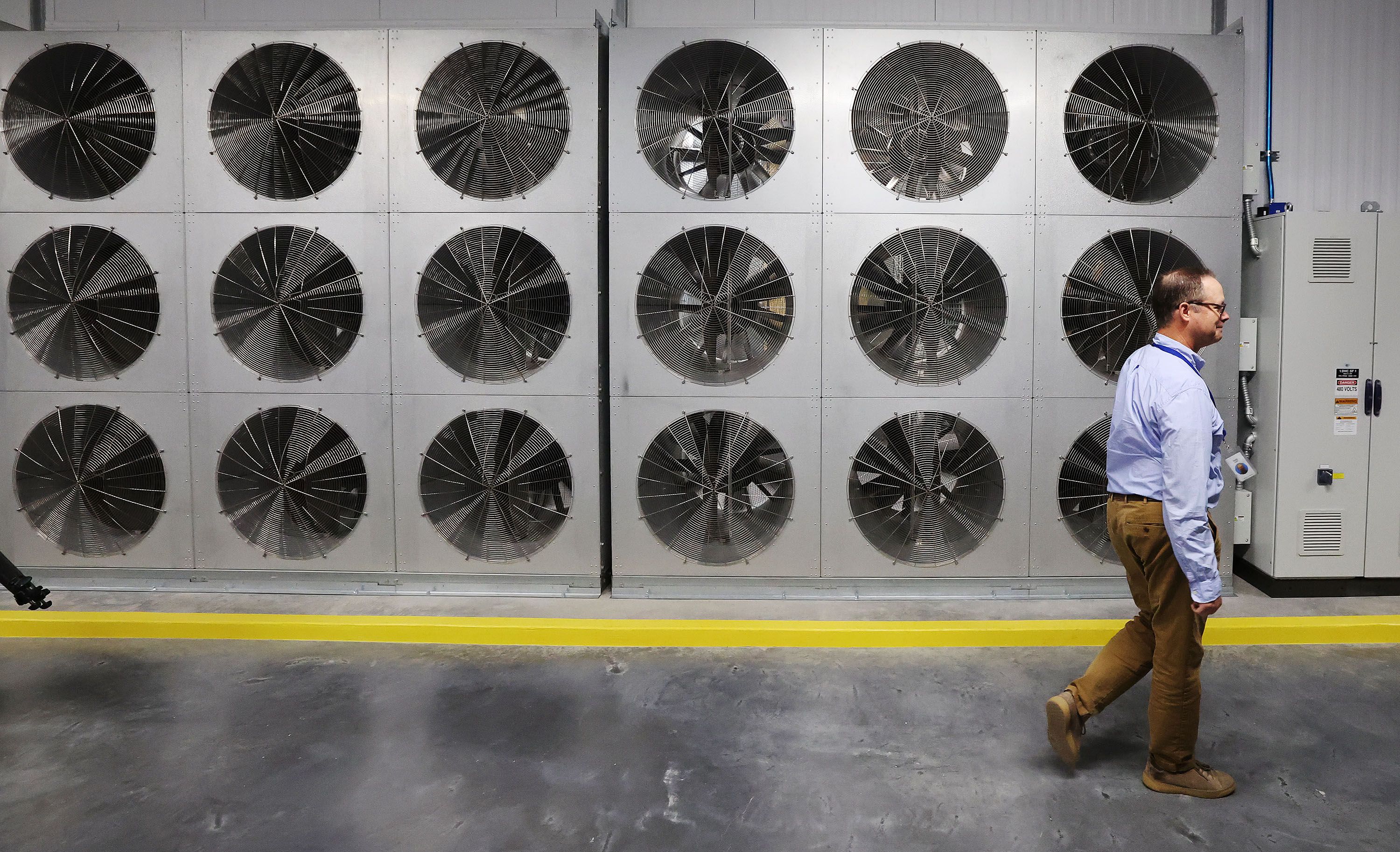 Data facilities manager Scott McLain walks past a fan wall used to cool servers used at Meta’s Eagle Mountain Data Center in Eagle Mountain on Friday. Meta is expanding the data center, increasing the total investment to over $1.5 billion. Once completed, the center will be a 4.5-million-square-foot campus.