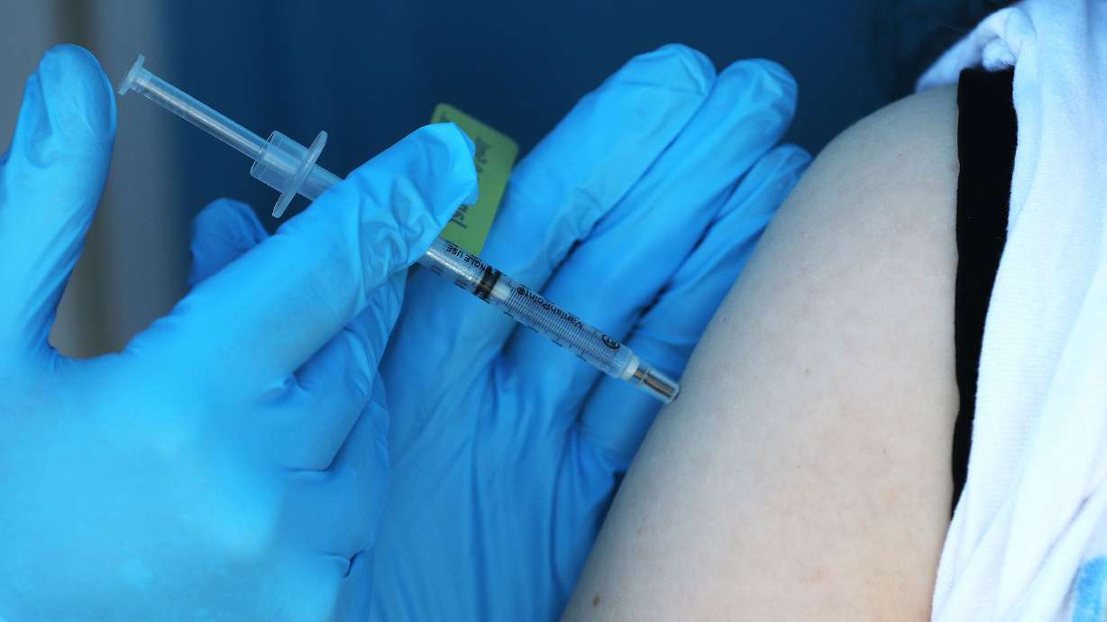 A COVID-19 booster vaccine is administered by a Nomi Health worker in West Valley City on July 14.