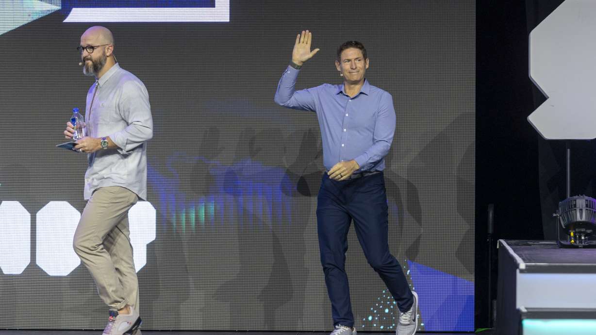 John Bowers, left, director of partnerships at Silicon Slopes, leads Steve Young, former BYU and NFL quarterback, onto the stage during the Silicon Slopes Summit at Vivint Arena in Salt Lake City on Friday.