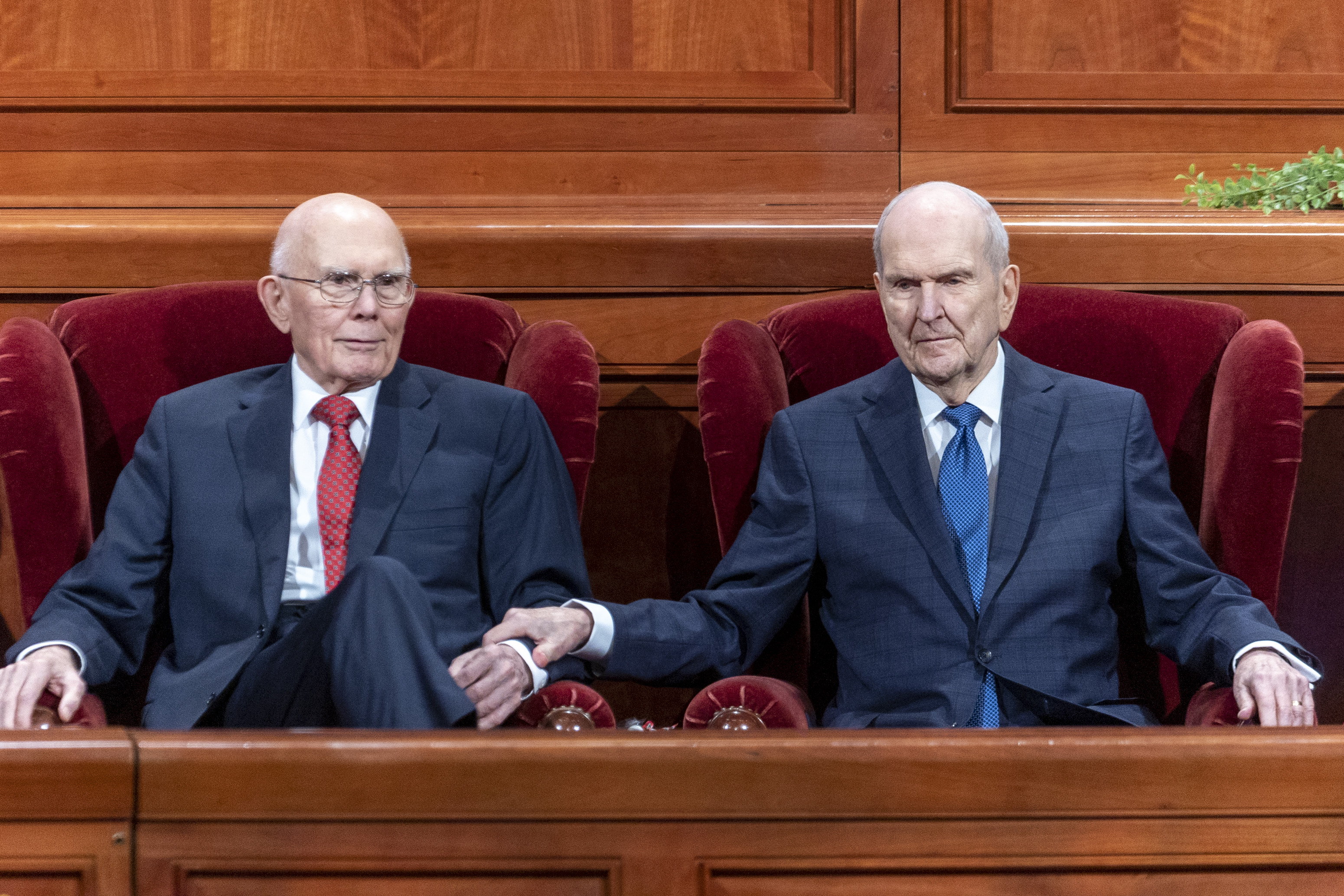 President Russell M. Nelson, right, reaches for President Dallin H. Oaks, first counselor, left, after he speaks during the Saturday evening session of general conference of The Church of Jesus Christ of Latter-day Saints in Salt Lake City on Saturday.