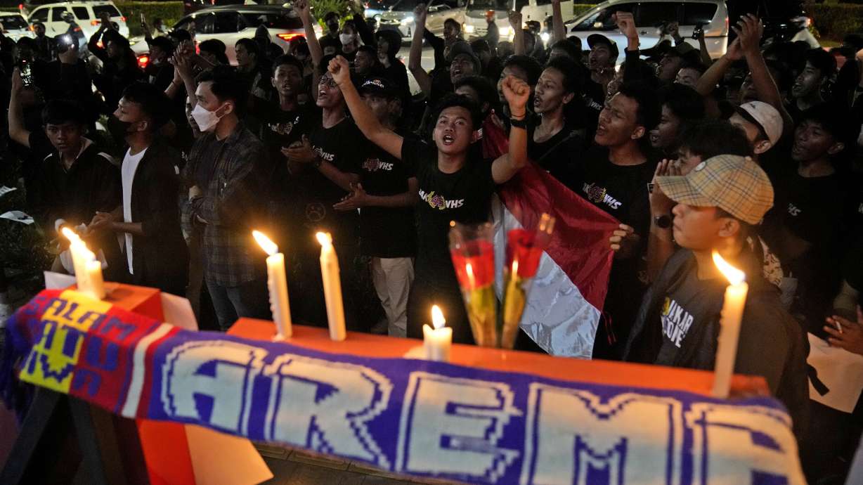 Soccer fans chant slogans during a candle light vigil for Arema FC Supporters who became victims of Saturday's soccer riots, outside the Youth and Sports Ministry in Jakarta, Indonesia, Sunday, Oct. 2, 2022. Panic and a chaotic run for exits after police fired tear gas at a soccer match between Arema FC and Persebaya in East Java to drive away fans upset with their team's loss left a large number of people dead, most of whom were trampled upon or suffocated.