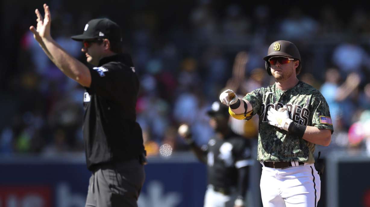 San Diego Padres' Jake Cronenworth, right, points toward the dugout after hitting a double against the Chicago White Sox as umpire Adam Beck calls time in the fourth inning a baseball game Sunday, Oct. 2, 2022, in San Diego.