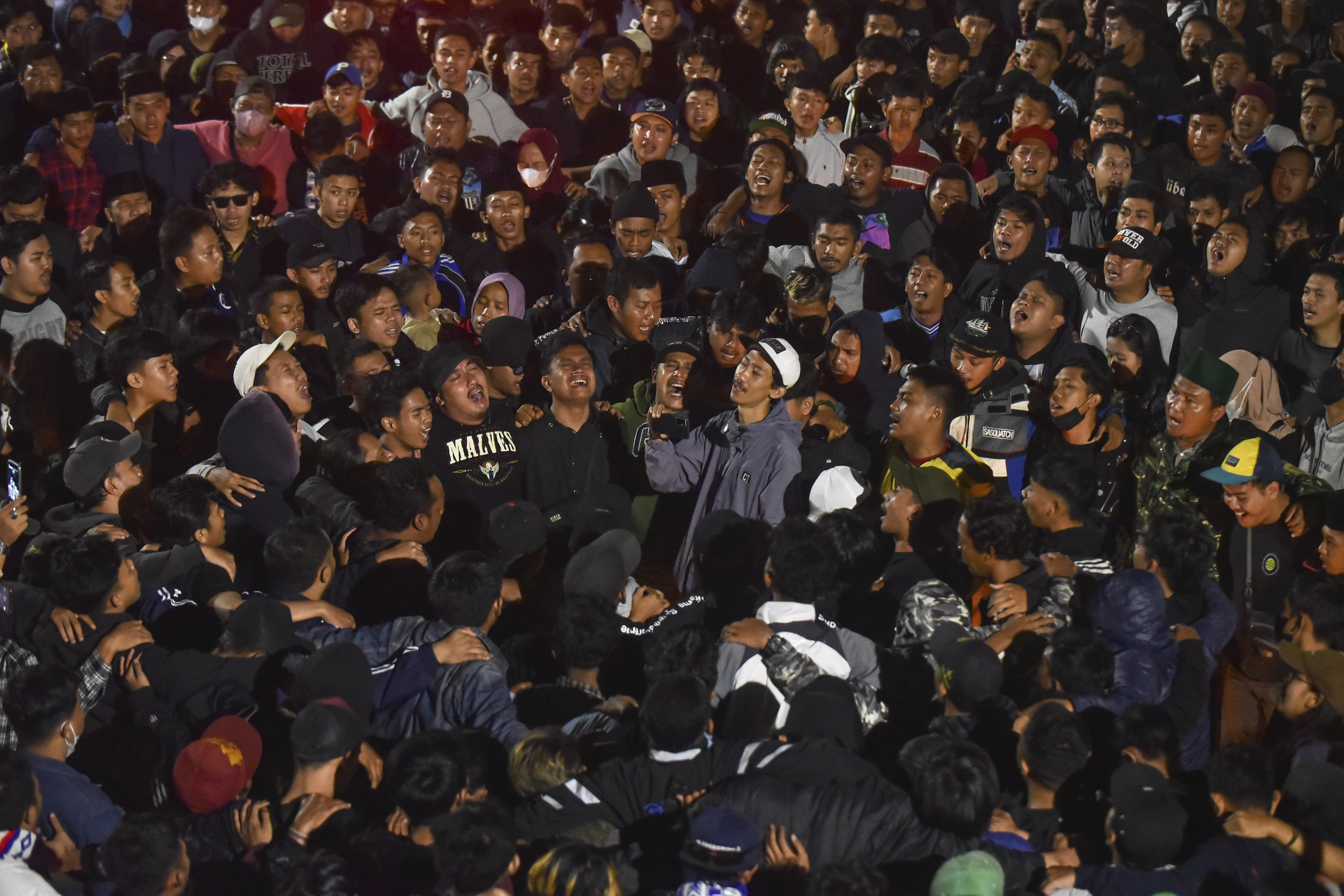 Soccer fans chant slogans during vigil for the victims of Saturday's soccer riots, in Malang, East Java, Indonesia, Sunday, Oct. 2, 2022. Police firing tear gas after an Indonesian soccer match in an attempt to stop violence triggered a disastrous crush of fans making a panicked, chaotic run for the exits, leaving a large number of people dead, most of them trampled upon or suffocated. 
