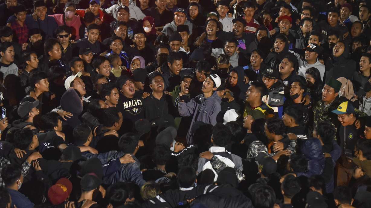 Soccer fans chant slogans during vigil for the victims of Saturday's soccer riots, in Malang, East Java, Indonesia, Sunday, Oct. 2, 2022. Police firing tear gas after an Indonesian soccer match in an attempt to stop violence triggered a disastrous crush of fans making a panicked, chaotic run for the exits, leaving a large number of people dead, most of them trampled upon or suffocated.