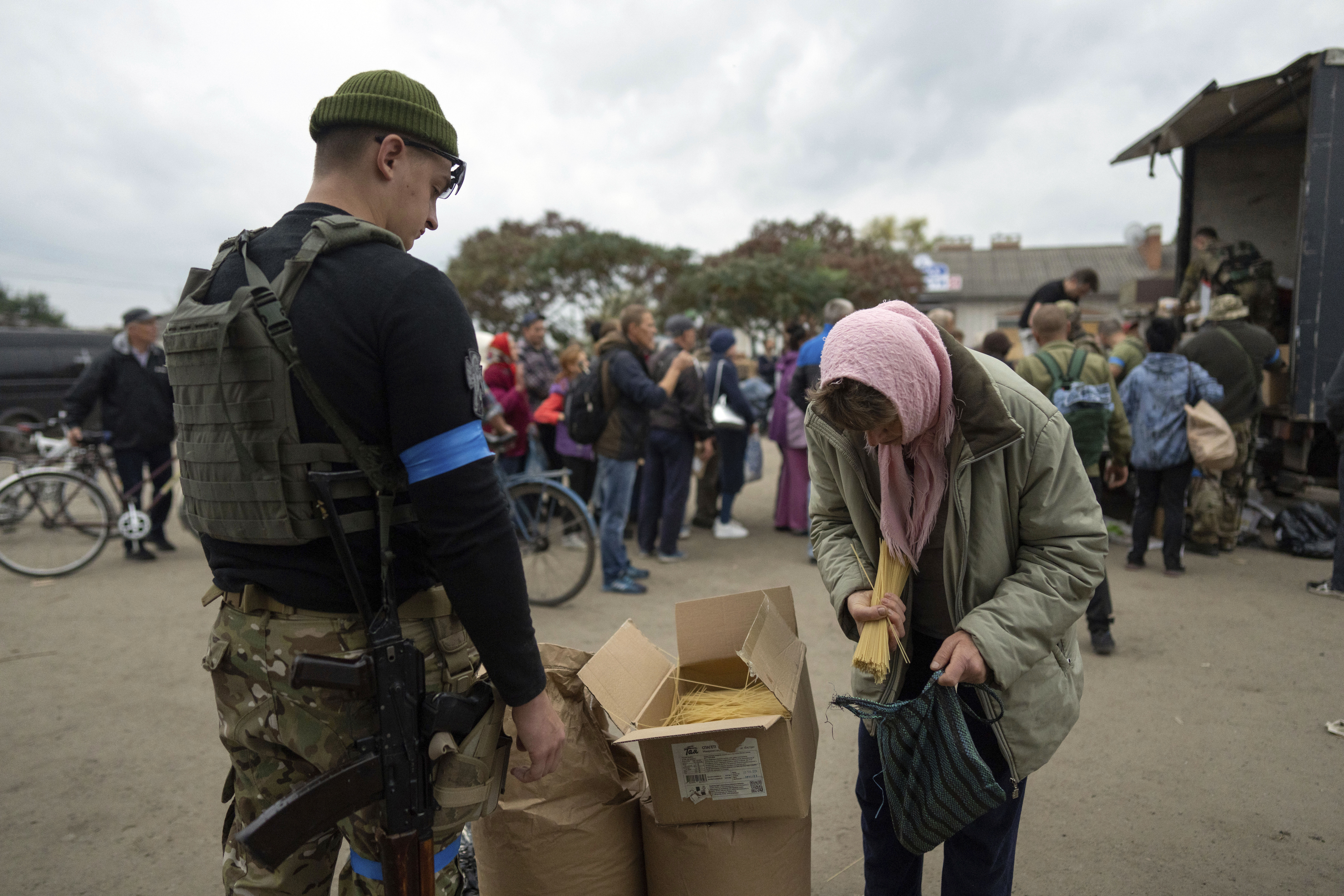 A Ukrainian serviceman of Sophia battalion distributes humanitarian aid to a local woman in the recently liberated town of Izium, Ukraine, Sunday.