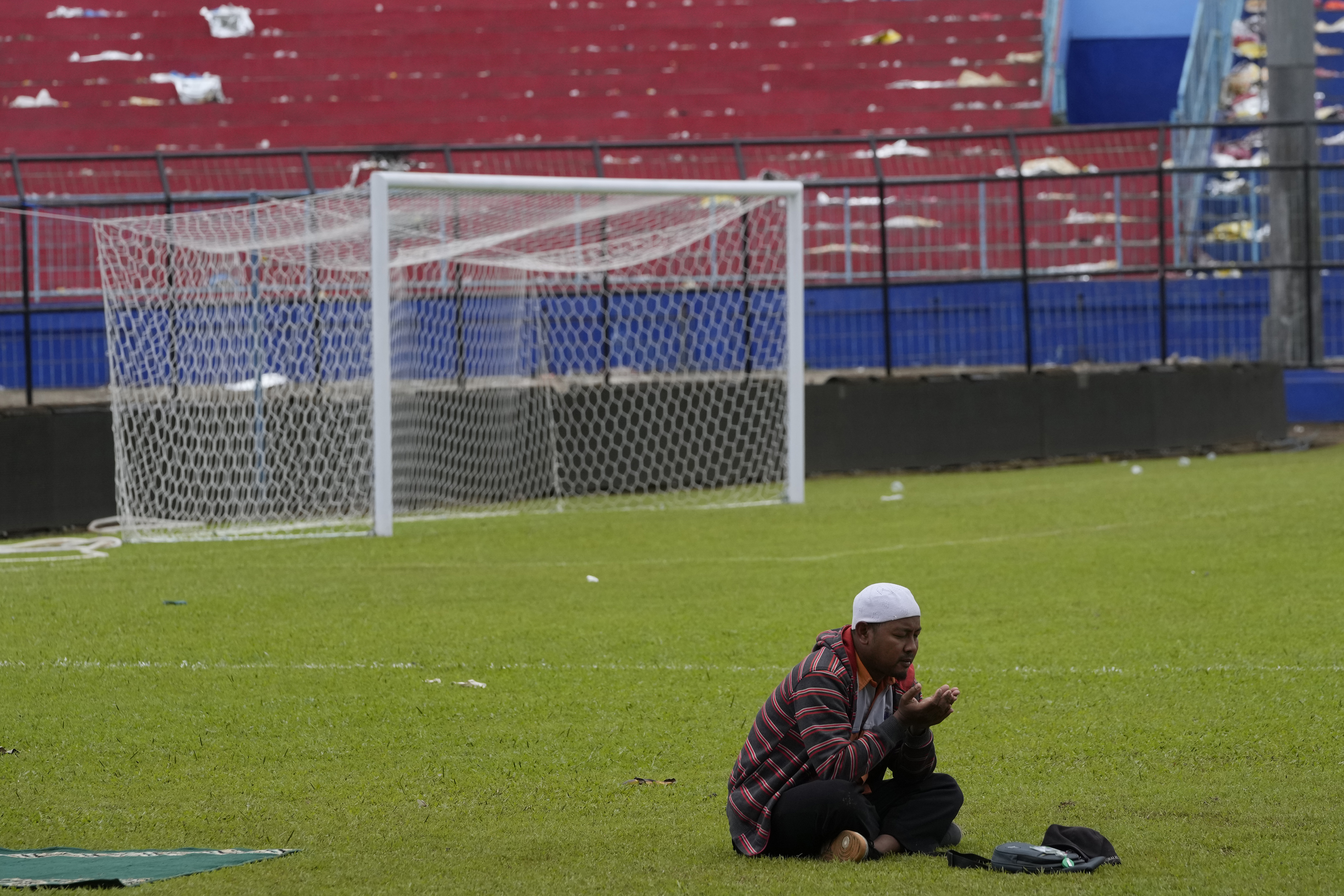 A supporter soccer club Arema FC prays for victims of Saturday's soccer match stampede inside the Kanjuruhan Stadium in Malang, Indonesia, Monday, Oct. 3, 2022. Panic at an Indonesian soccer match Saturday left over 100 people dead, most of whom were trampled to death after police fired tear gas to stop the violence. 