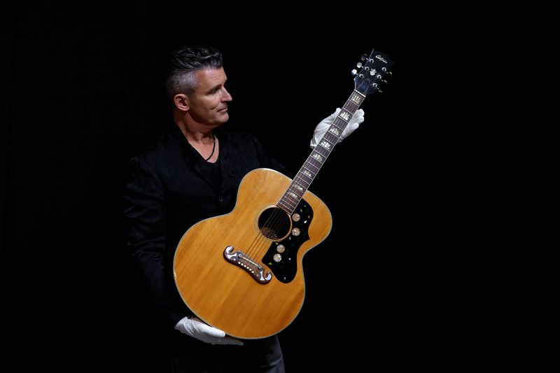 Propstore CEO Stephen Lane holds one of three Oasis "Wonderwall" music video screen and photo matched guitars played by Noel Gallagher at a Propstore facility in Rickmansworth, Britain, Sept. 27.