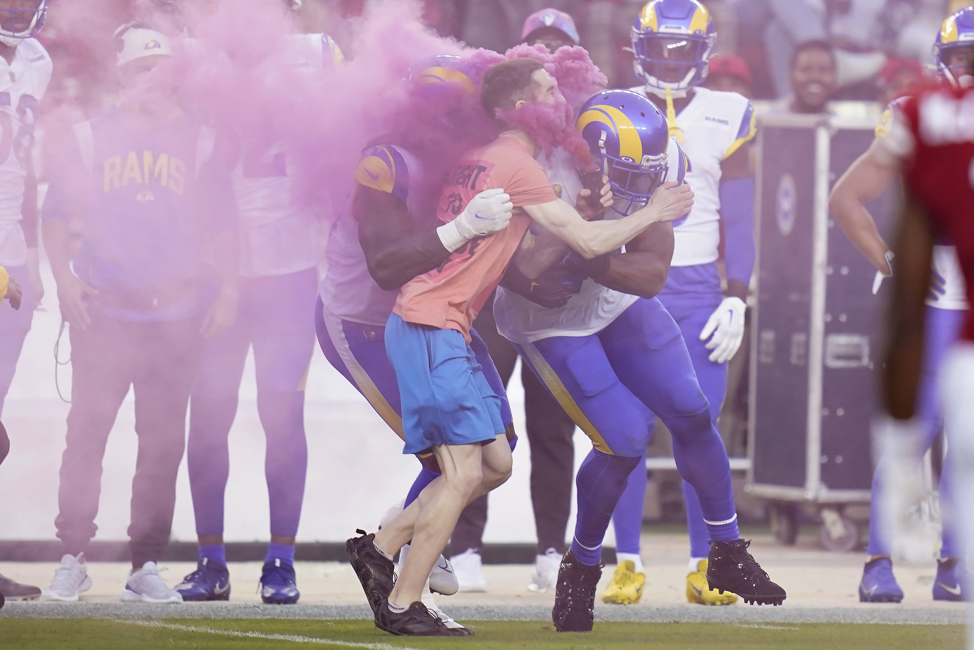 A protester is hit by Los Angeles Rams defensive end Takkarist McKinley, middle left, and linebacker Bobby Wagner during the first half of an NFL football game between the San Francisco 49ers and the Rams in Santa Clara, Calif., Monday, Oct. 3, 2022. 