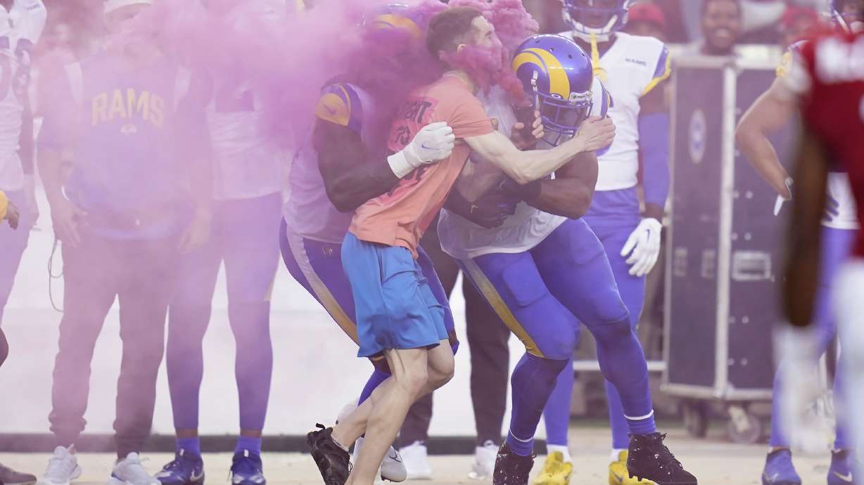 A protester is hit by Los Angeles Rams defensive end Takkarist McKinley, middle left, and linebacker Bobby Wagner during the first half of an NFL football game between the San Francisco 49ers and the Rams in Santa Clara, Calif., Monday, Oct. 3, 2022.