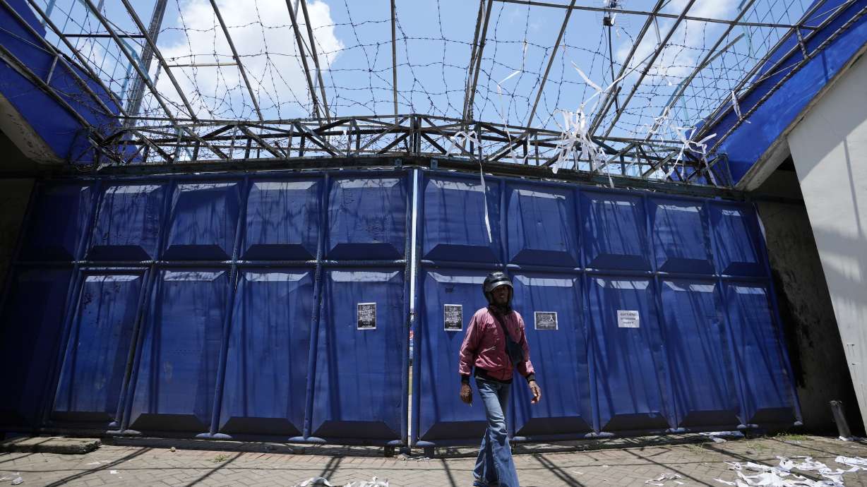 A man walks in front of gate at the Kanjuruhan Stadium in Malang, Indonesia, Tuesday, Oct. 4, 2022. A police chief and nine elite officers were removed from their posts Monday and 18 others were being investigated for responsibility in the firing of tear gas inside a soccer stadium that set off a stampede, killing over 100 people, officials said.