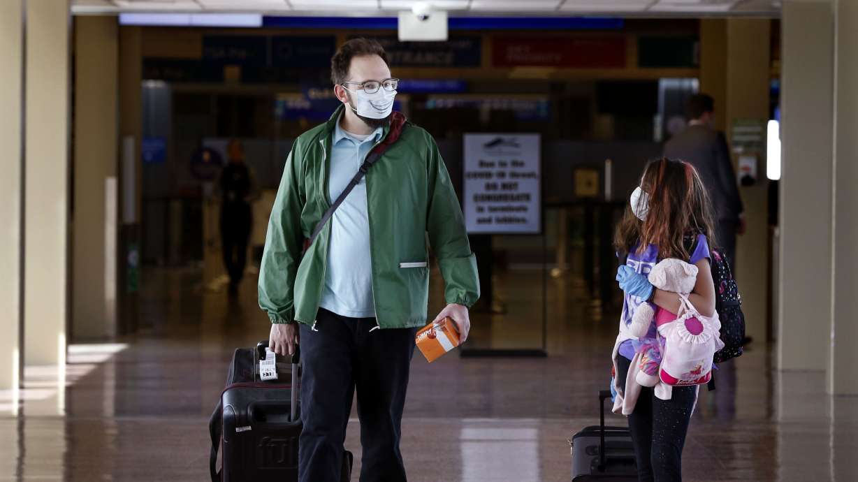 Matt Lemmon and his daughter Celeste walk through the Salt Lake City International Airport on April 8, 2020. Lemmon decorated his face mask to surprise his daughter, who he was picking up at the airport. The CDC has stopped issuing regular COVID-19-related advisories for international travelers.