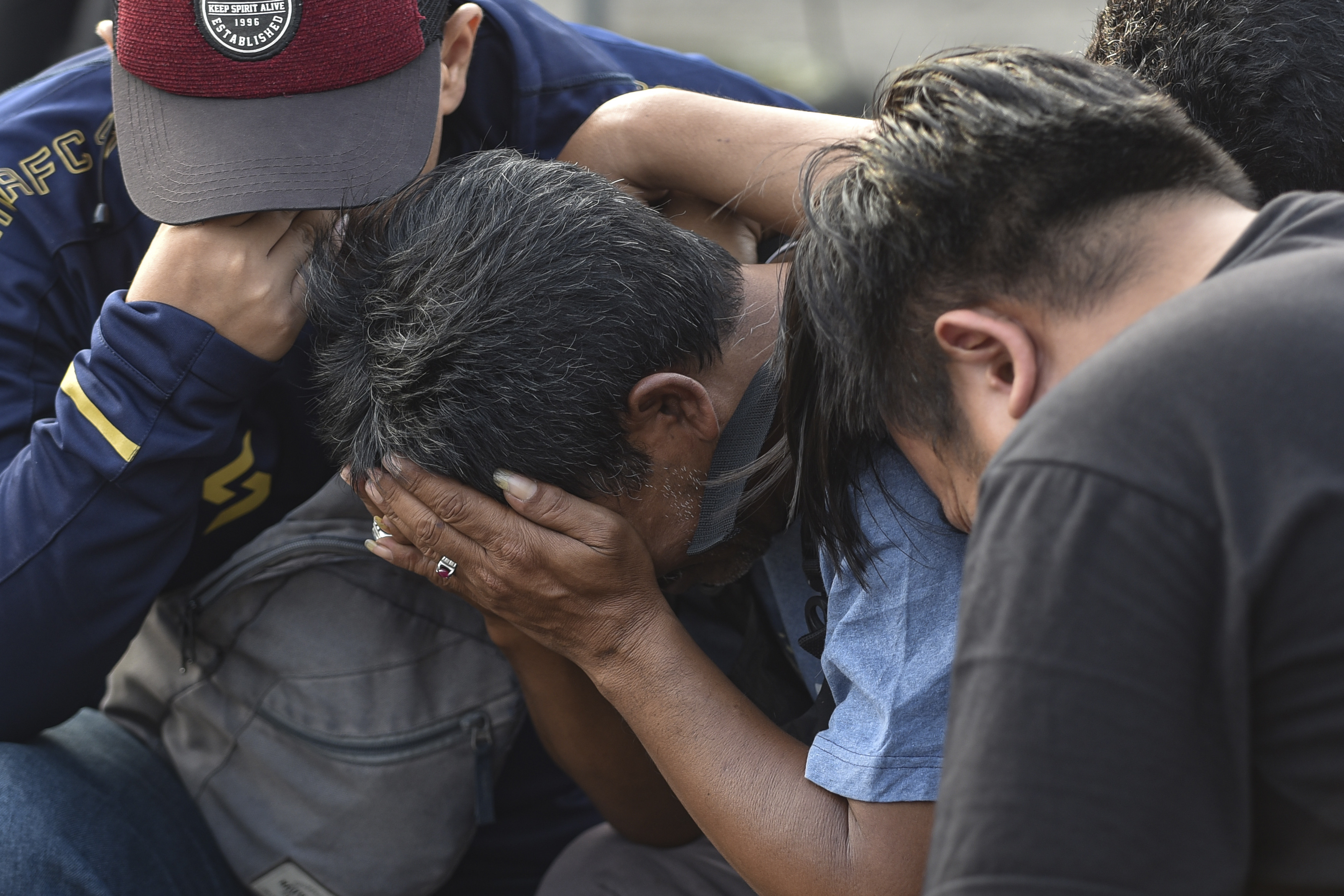 Men weep as they offer prayer outside Kanjuruhan Stadium where a soccer stampede killed more than 100 people on Saturday, in Malang, East Java, Indonesia, Tuesday, Oct. 4, 2022. Police firing tear gas inside the stadium on Saturday in an attempt to stop violence after an Indonesian soccer match triggered a disastrous crush of fans making a panicked, chaotic run for the exits, leaving at a number of people dead, most of them trampled upon or suffocated.