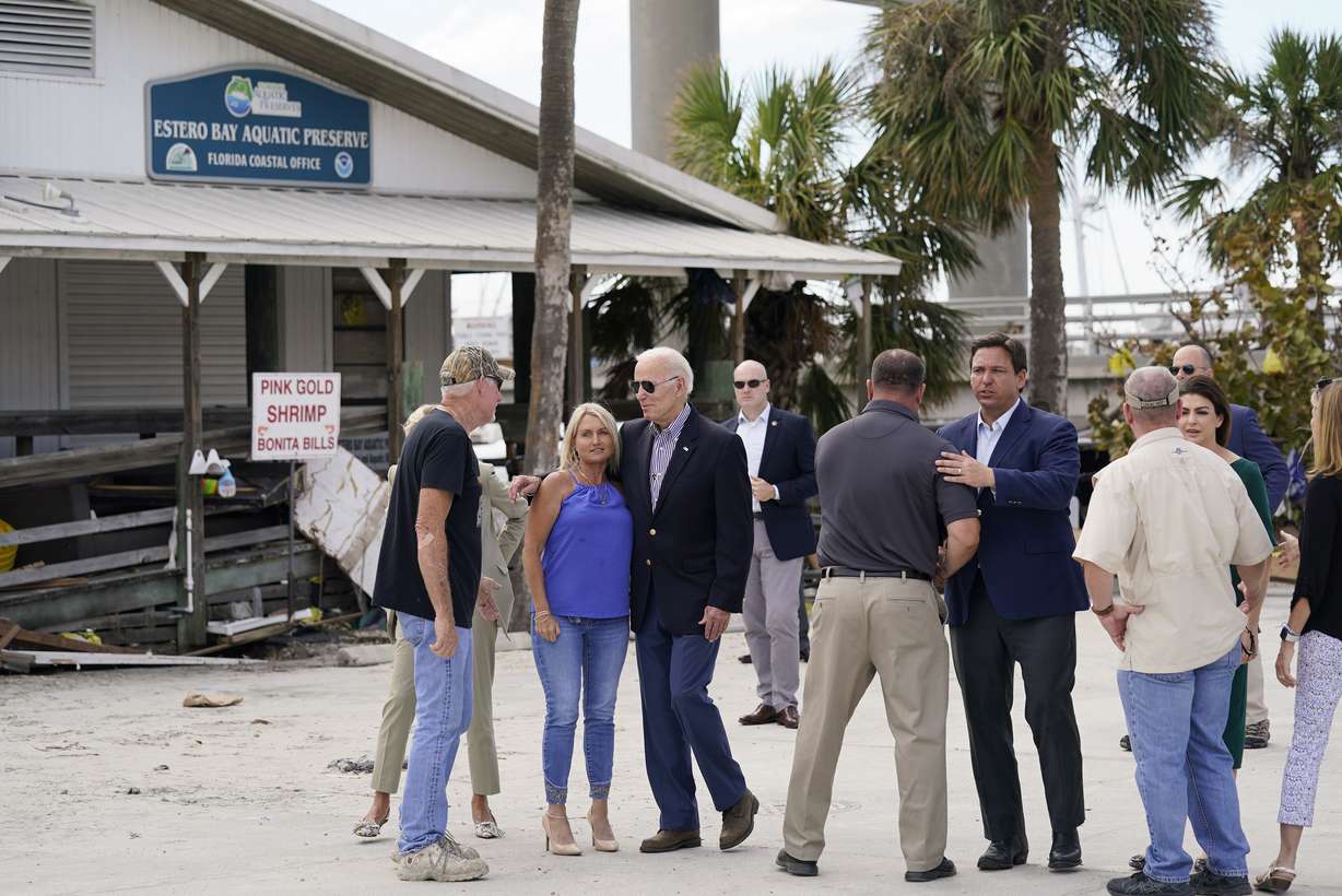 President Joe Biden and Florida Gov. Ron DeSantis talk to people impacted by Hurricane Ian during a tour of the area on Wednesday in Fort Myers Beach, Fla.