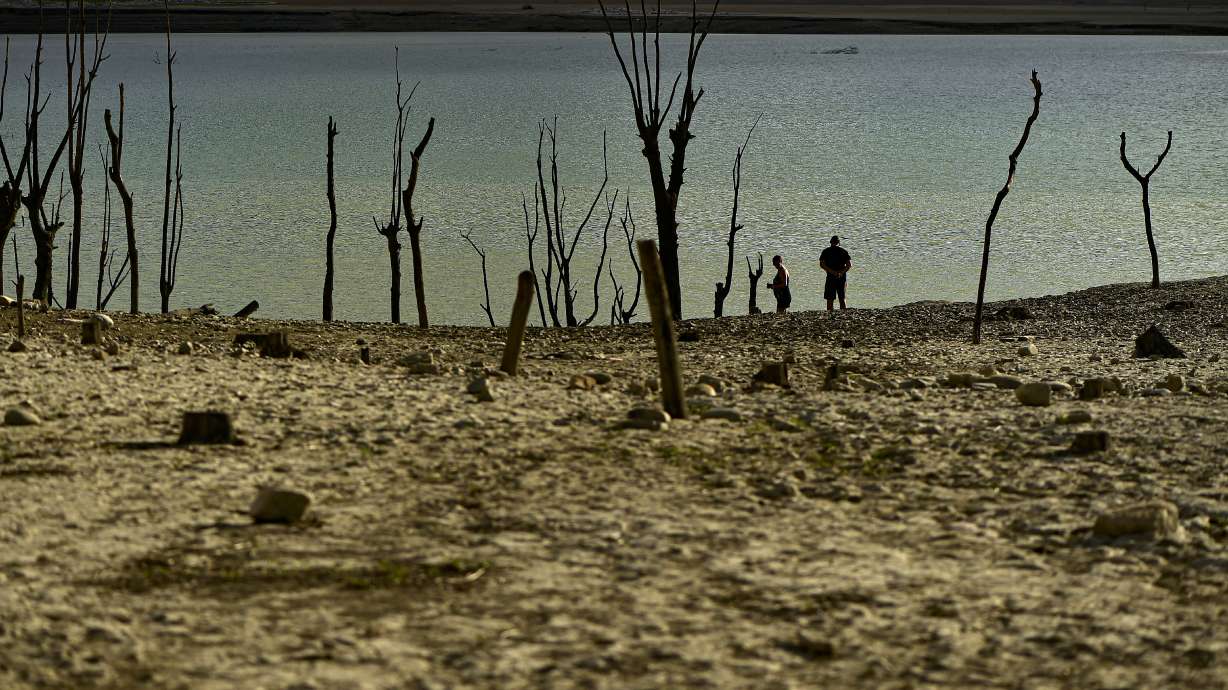 People walk close to the border at Yesa's reservoir affected by drought, on a sunny summer day in Yesa, around 34 miles, from Pamplona, northern Spain, Sept. 14. Widespread drought that dried up large parts of Europe, the United States and China this past summer was made 20 times more likely by climate change, according to a new study.