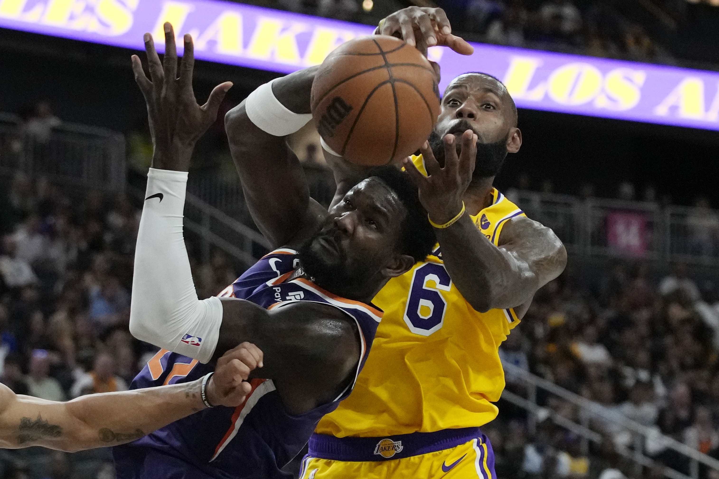 Phoenix Suns center Deandre Ayton (22) and Los Angeles Lakers forward LeBron James (6) battle for the ball during the first half of a preseason NBA basketball game Wednesday, Oct. 5, 2022, in Las Vegas. 