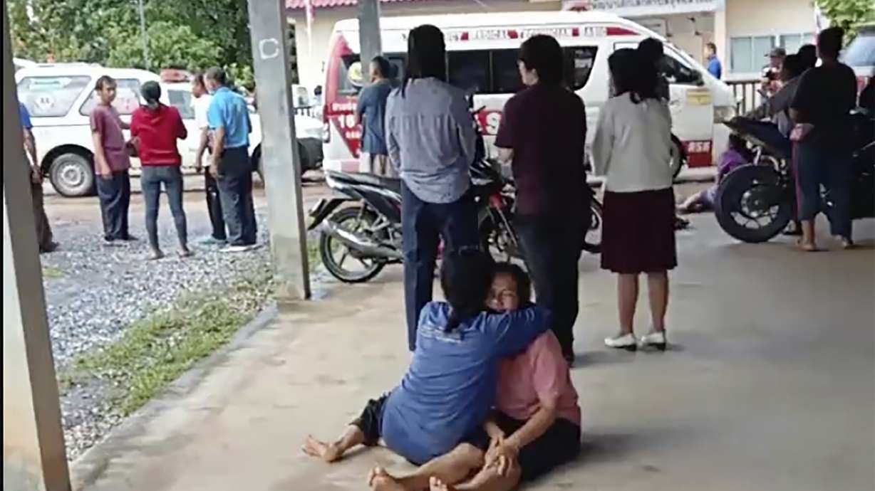 In this image taken from video, a distraught woman is comforted outside the site of an attack at a day care center, Thursday, in the town of Nongbua Lamphu, northeastern Thailand. More than 30 people, primarily children, were killed Thursday when a gunman opened fire in the child care center authorities said.