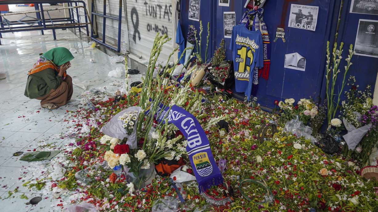 A woman prays near one of the gates of Kanjuruhan Stadium where a soccer stampede killed more than 100 people on Saturday, in Malang, East Java, Indonesia, Thursday, Oct. 6, 2022. Police firing tear gas inside the stadium on Saturday after a soccer match triggered the disastrous crush of fans making a panicked, chaotic run for the exits, leaving hundreds dead and injured.