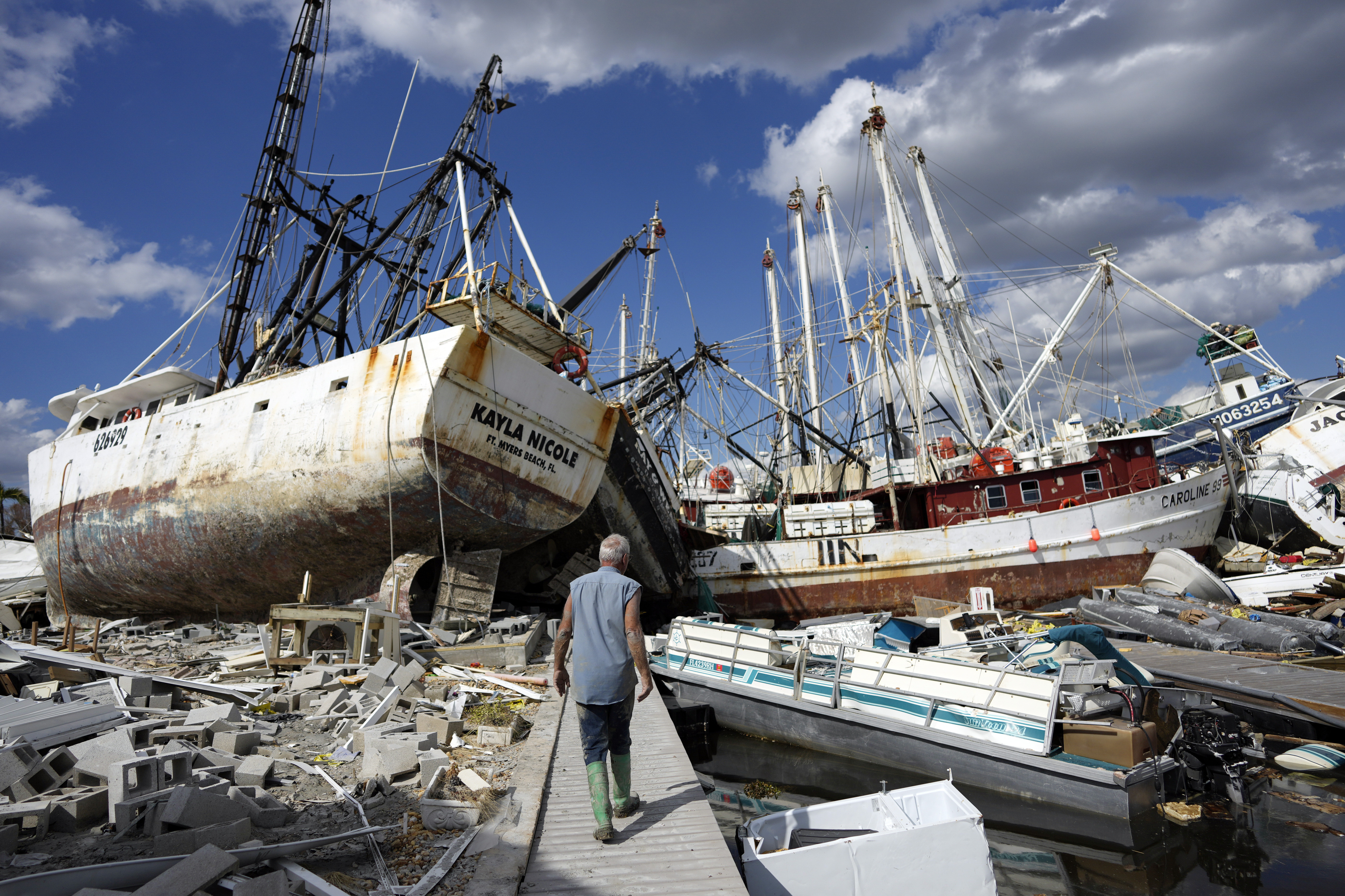 Snowbird Bruce Hickey, 70, walks along the waterfront, now littered with debris including shrimp boats, on San Carlos Island, Fort Myers Beach, Fla., Wednesday, one week after the passage of Hurricane Ian. 
