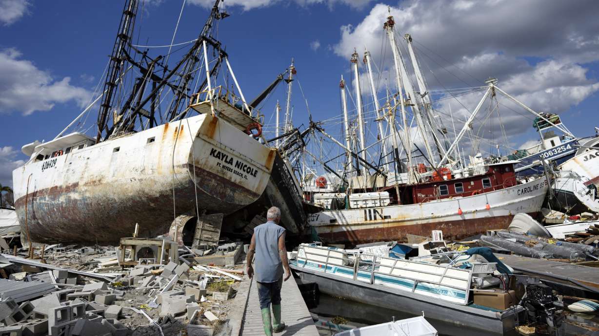 Snowbird Bruce Hickey, 70, walks along the waterfront, now littered with debris including shrimp boats, on San Carlos Island, Fort Myers Beach, Fla., Wednesday, one week after the passage of Hurricane Ian.