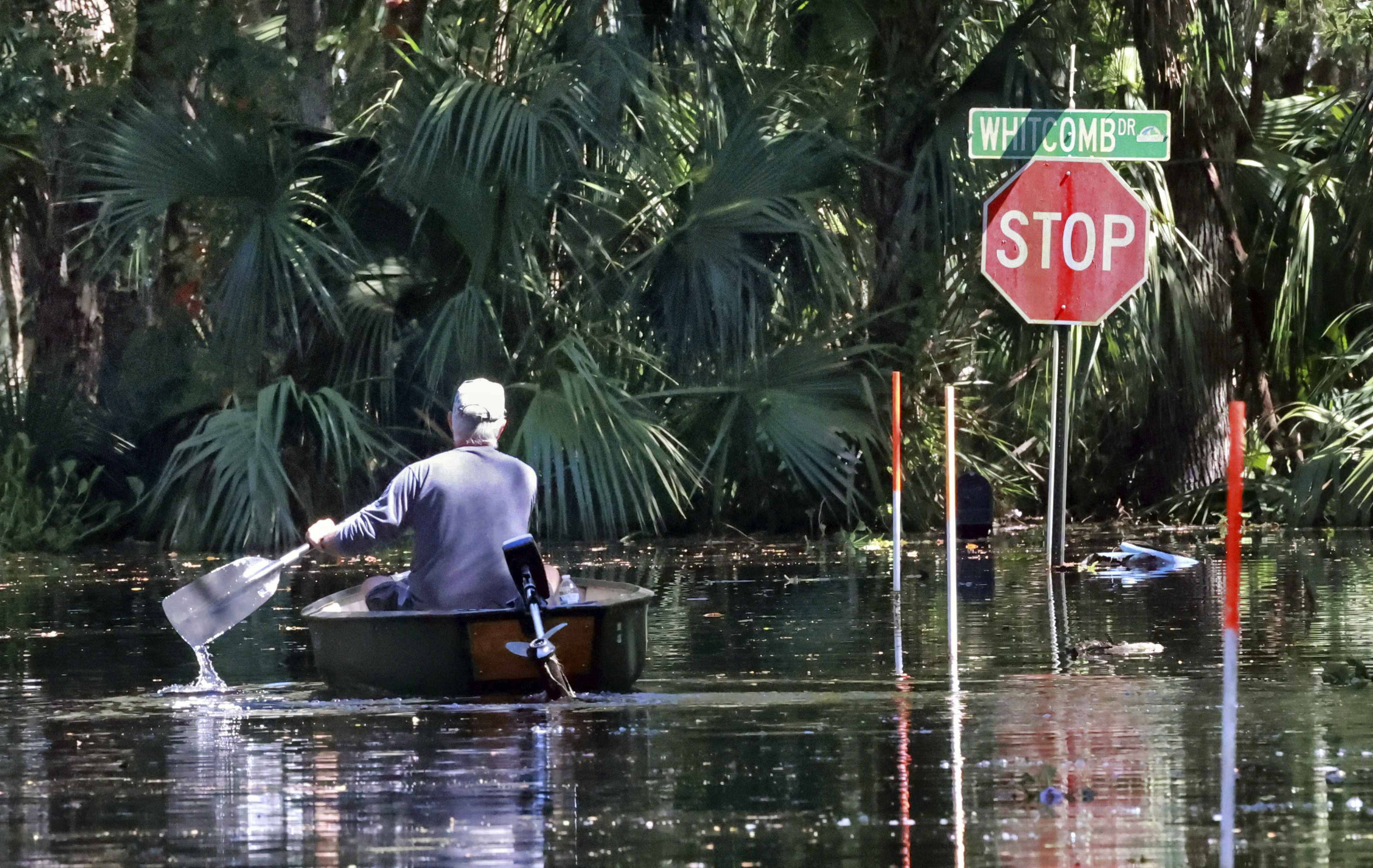 A resident navigates a canoe to his flooded home on Whitecomb Drive along the shore of Lake Harney in Geneva, Fla., Thursday.