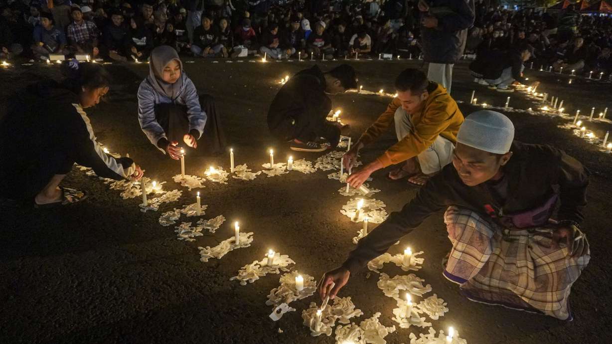 People light candles during a vigil at Kanjuruhan Stadium in Malang, East Java, Indonesia, Friday, Oct. 7, 2022. Indonesian police said they are bringing criminal charges against three officers and three civilians for their roles in the deaths of more than 100 people when police fired tear gas in the soccer stadium after a match on Saturday, setting off a panicked run for the exits in which many were crushed.