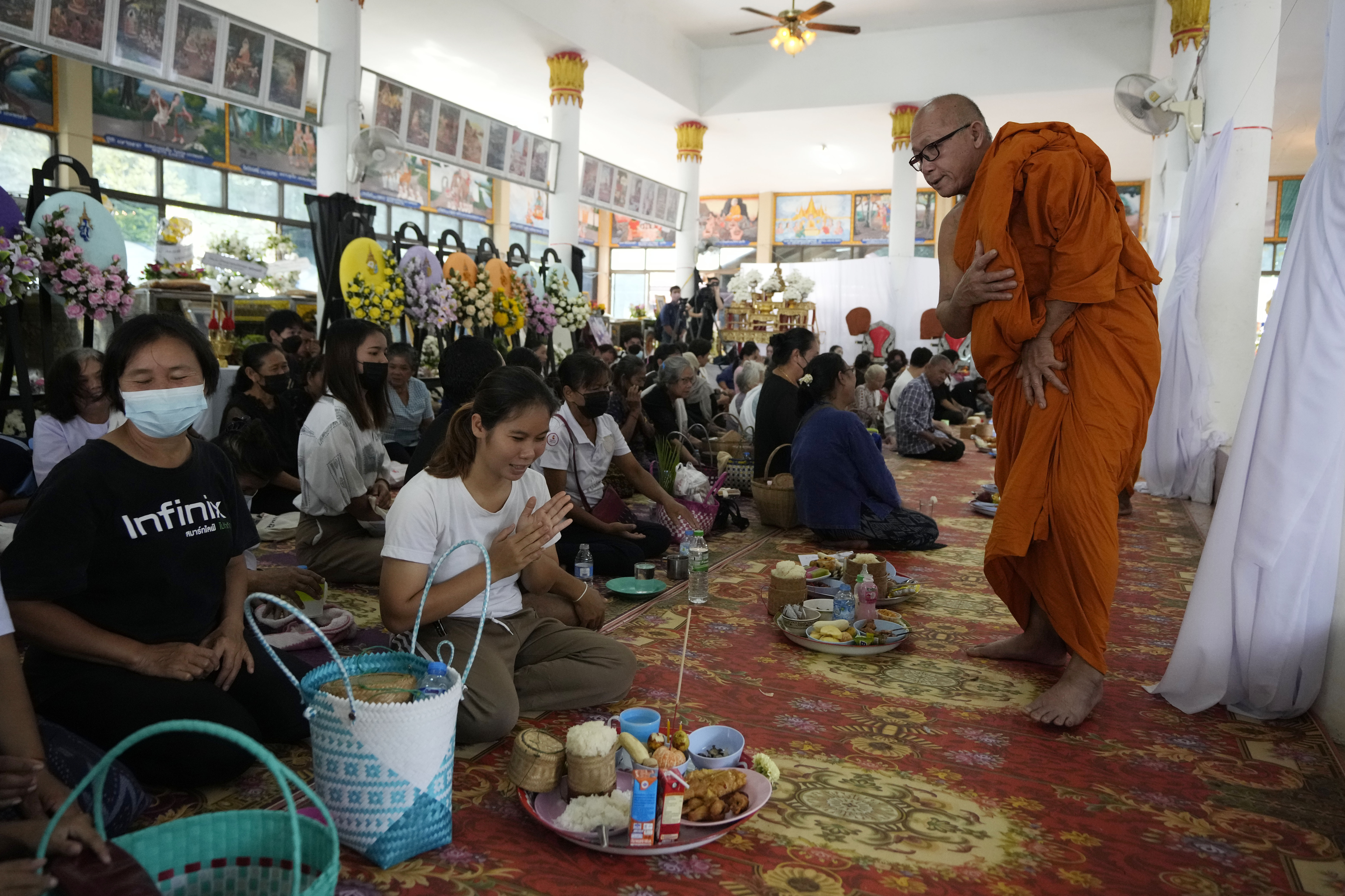A Buddhist monk speaks with relatives of the victims of a mass killing attack gather for a Buddhist ceremony inside Wat Rat Samakee temple in the rural town of Uthai Sawan, north eastern Thailand, Sunday. A former police officer burst into a day care center in northeastern Thailand on Thursday, killing dozens of preschoolers and teachers before shooting more people as he fled.
