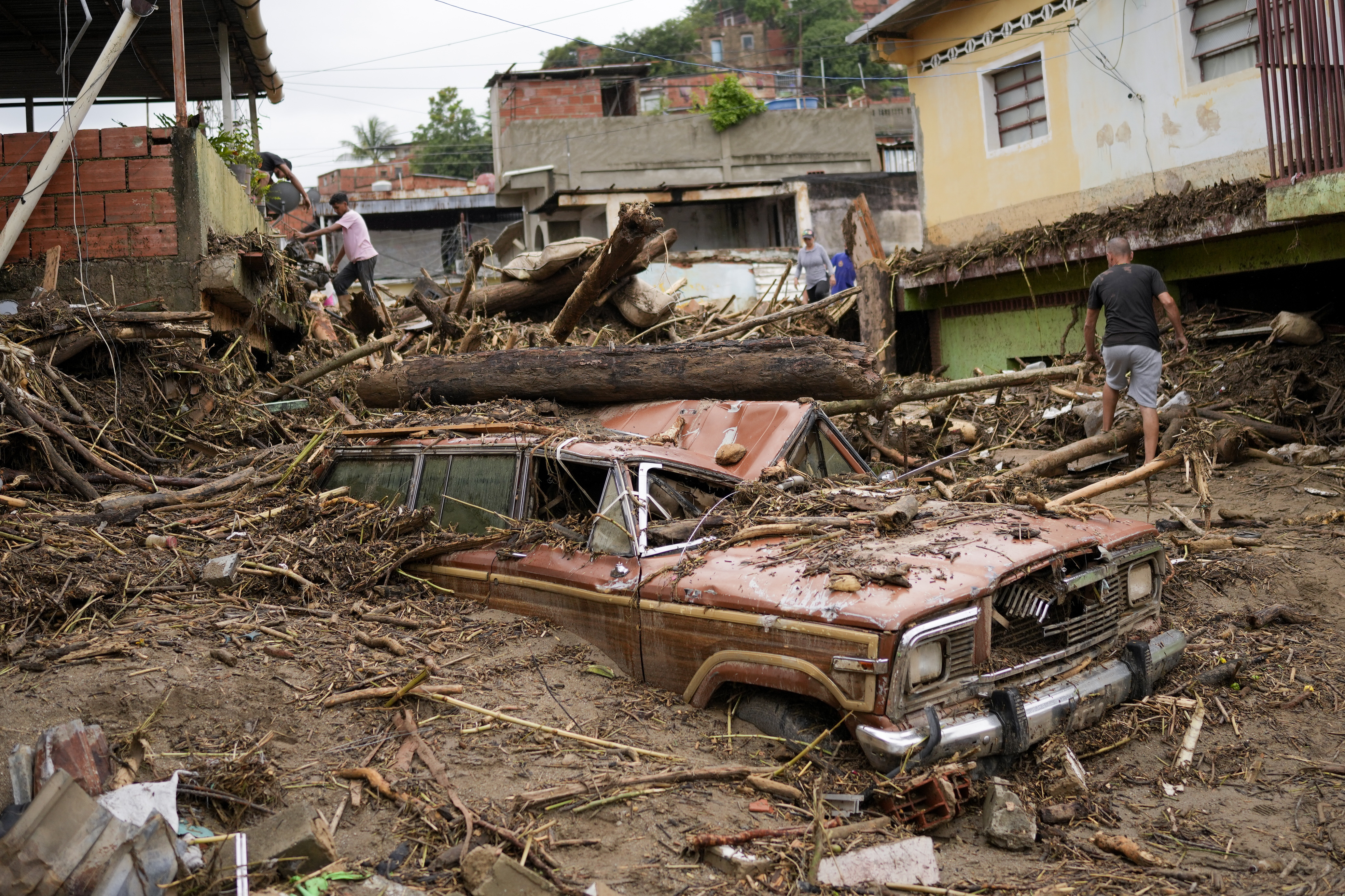 Residents walk through the debris left by flooding caused by a river that overflowed after days of intense rain in Las Tejerias, Venezuela, Sunday. 