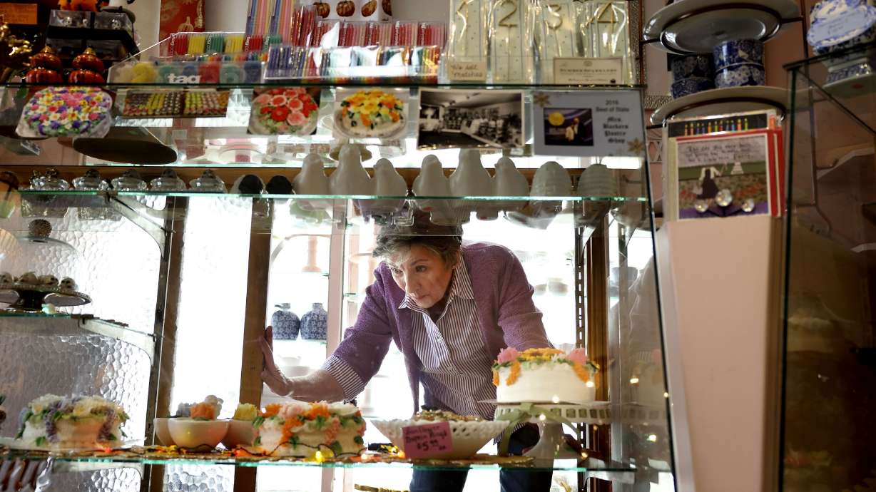 Renee Backer places cakes in the display cabinet at Backer’s Pastry Shop in Salt Lake City on Wednesday.
