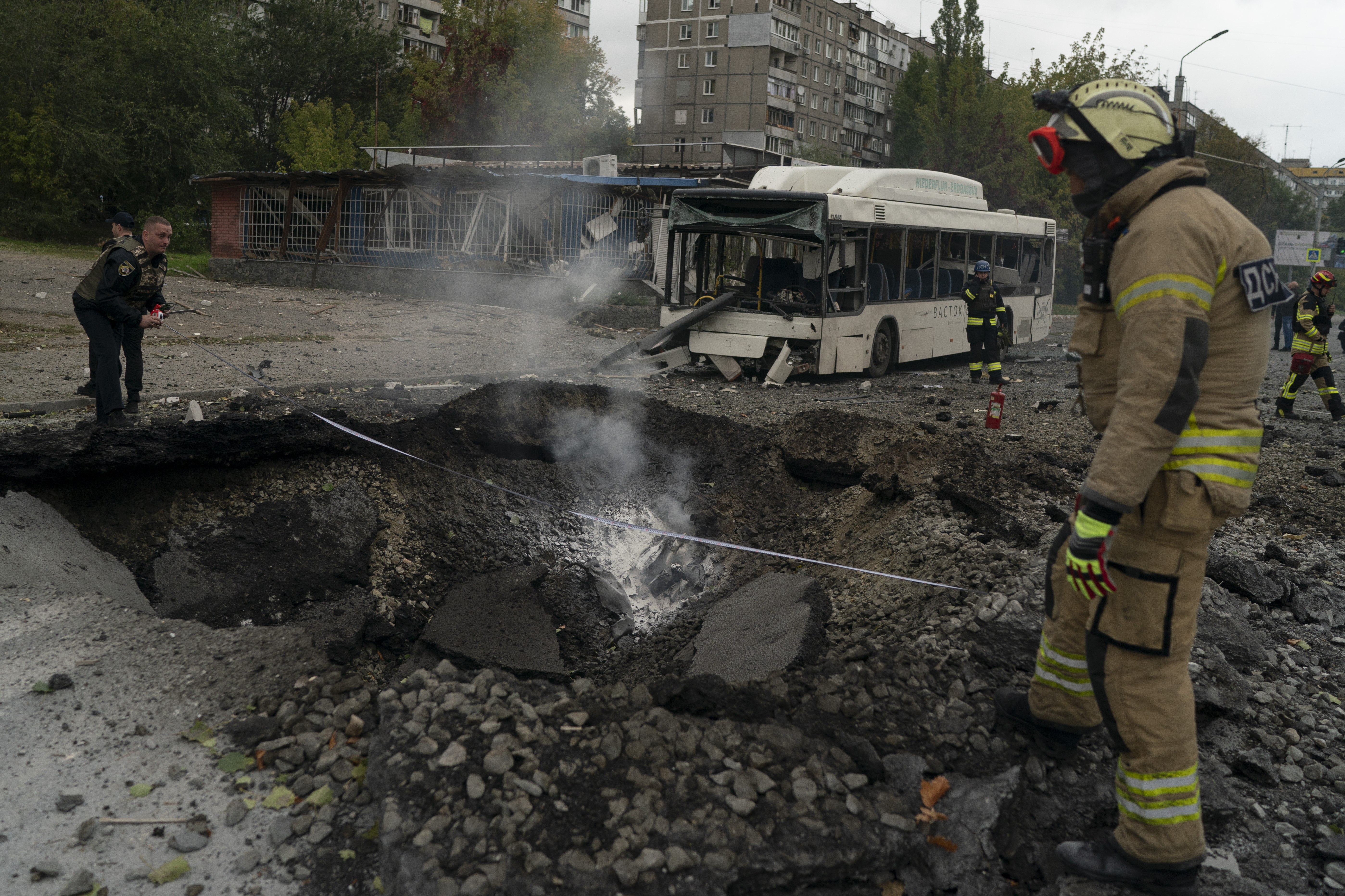 Firefighters and police officers work on a site where an explosion created a crater on the street after a Russian attack in Dnipro, Ukraine, Monday.