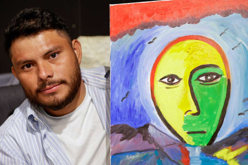 Walter Cifuentes García poses next to one of his paintings at The Leonardo in Salt Lake City on Saturday.