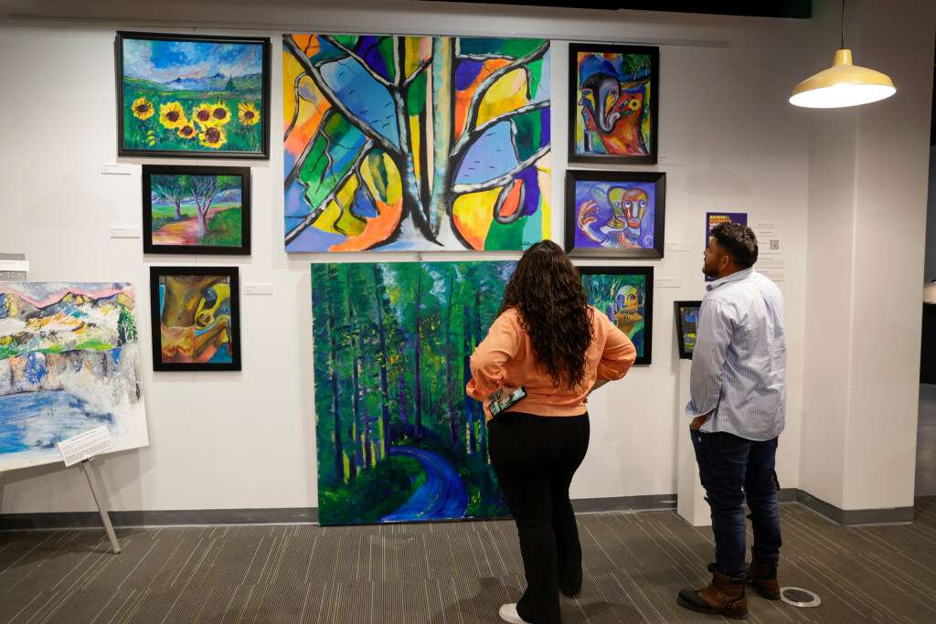 Andrea Silva, marketing and communication manager of Artes de México en Utah, left, talks with artist Walter Cifuentes García as the two look at Cifuentes' hanging work at The Leonardo in Salt Lake City on Saturday.
