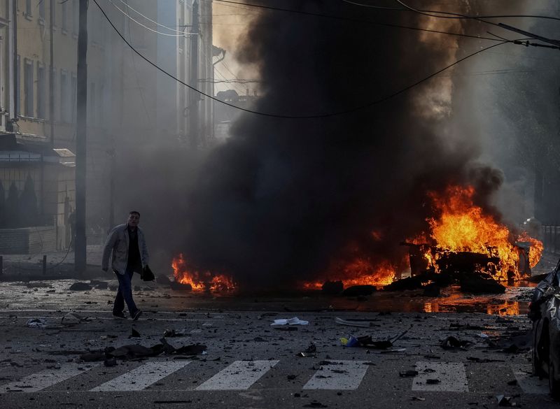 A driver walks near his burned car after Russian military strike, as Russia's invasion of Ukraine continues, in central Kyiv, Ukraine Oct. 10.