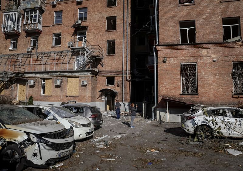 Local residents stand near their apartment building, damaged by the previous day's Russian military strike, as Russia's attack on Ukraine continues, in central Kyiv, Ukraine, on Tuesday.