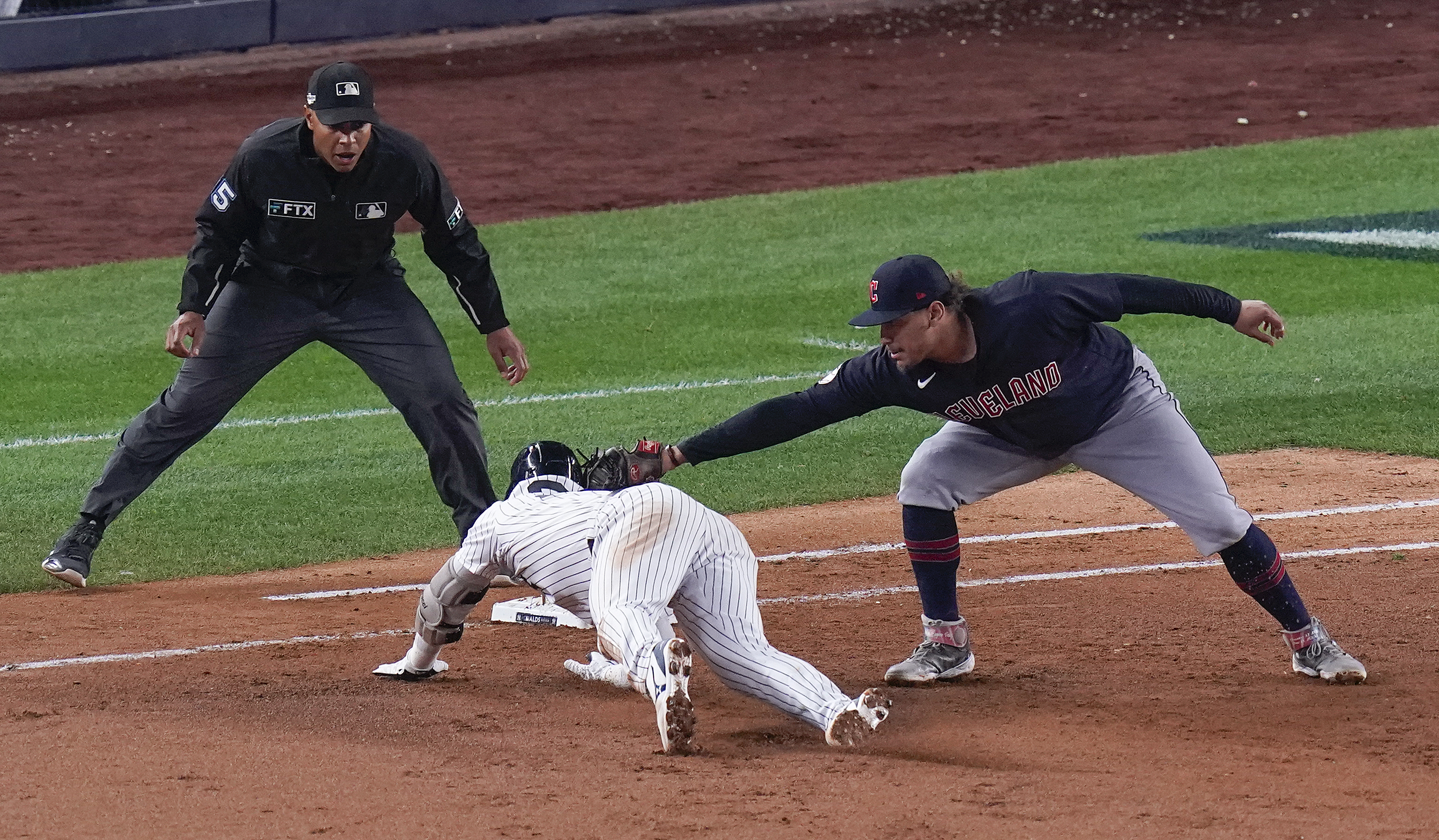 New York Yankees Josh Donaldson is tagged out by Cleveland Guardians first baseman Josh Naylor as he tries to get back to the first base bag after hitting a single off the right field wall during the fifth inning of Game 1 of an American League Division baseball series, Tuesday, Oct. 11, 2022, in New York. 